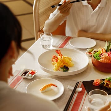 a group of people eating sushi at a table