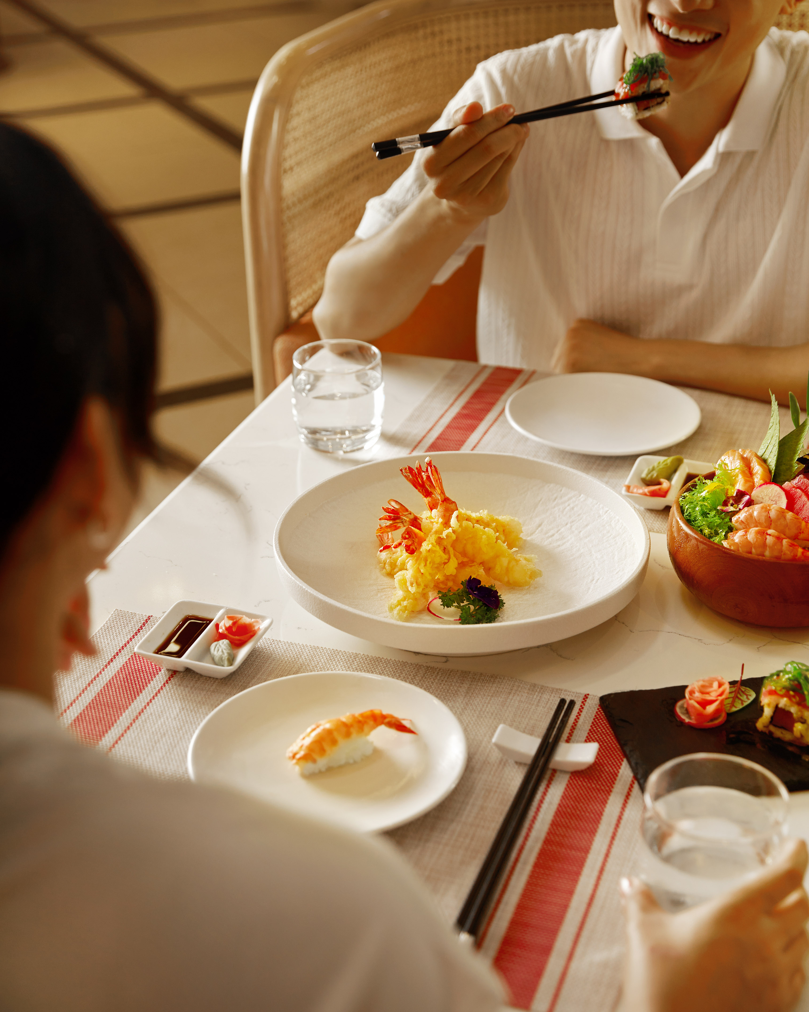 Diners enjoying a Japanese meal: sushi, sashimi, and crispy shrimp tempura.