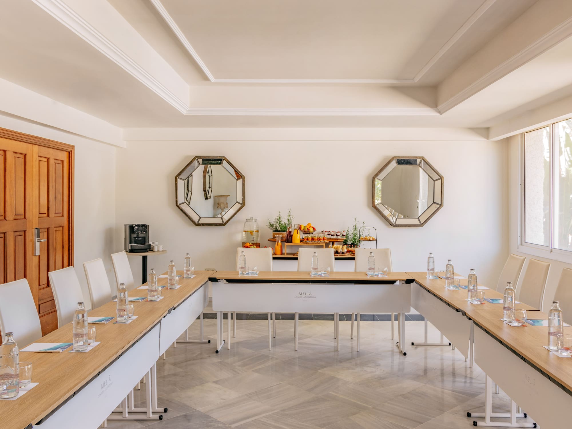 Melia conference room with U-shaped table setup, refreshments, and natural light.