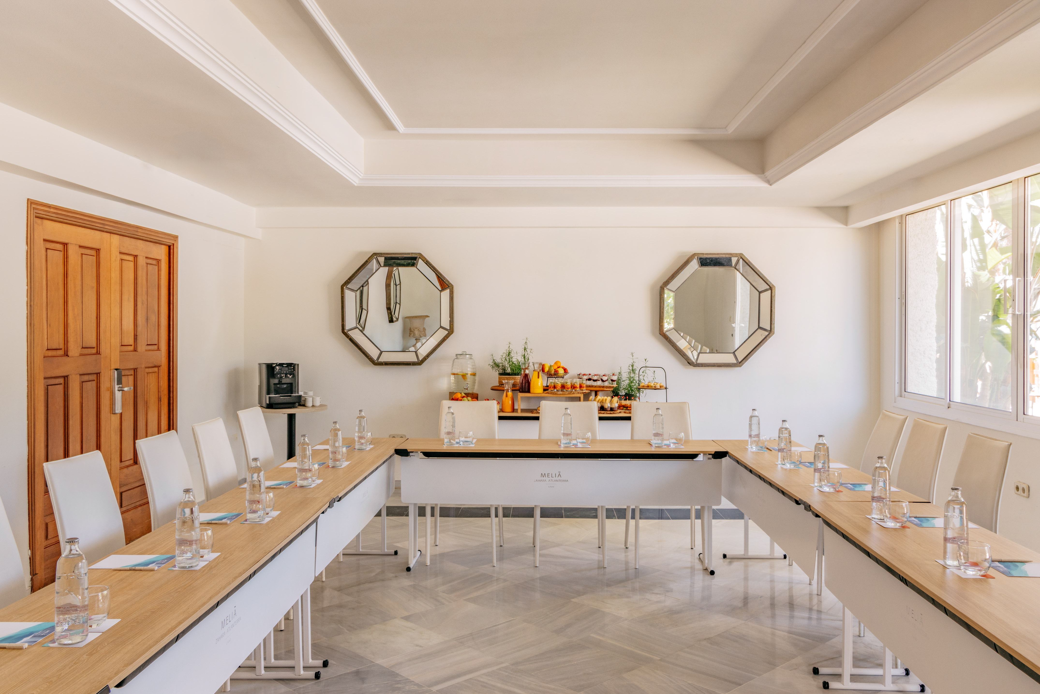 Melia conference room with U-shaped table setup, refreshments, and natural light.