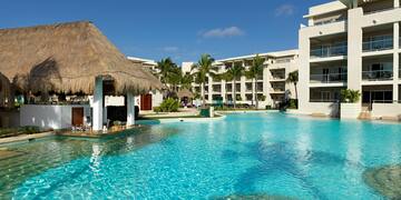 a pool with a straw roof and a building