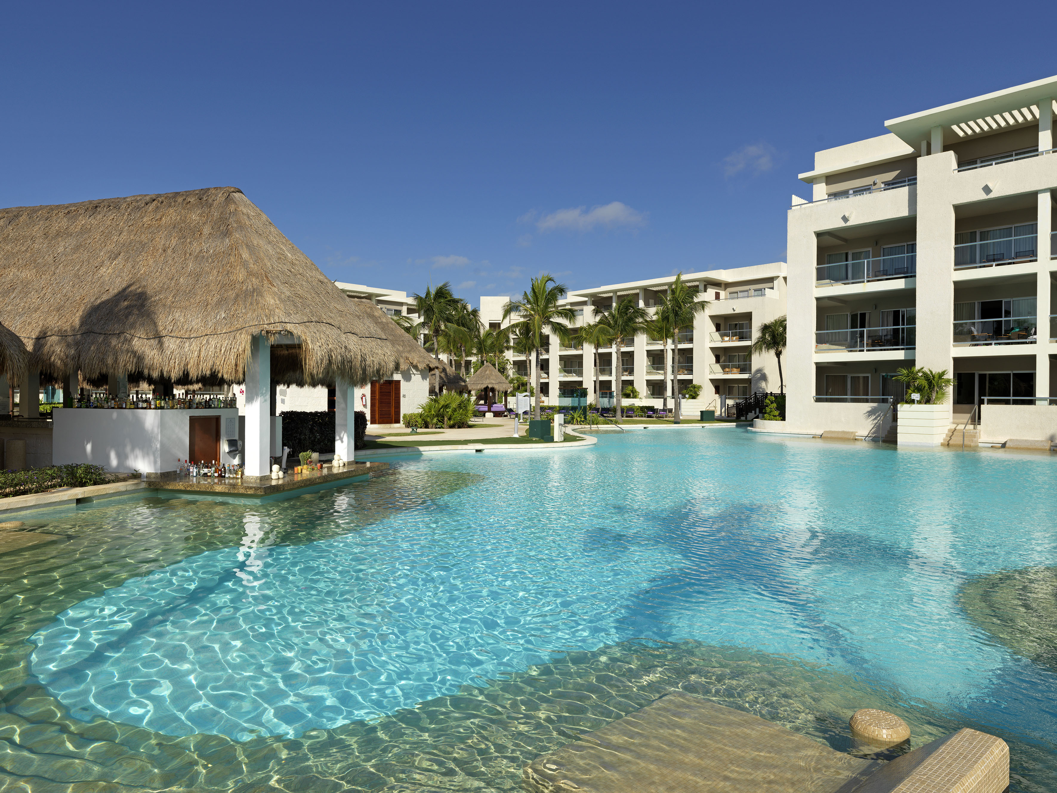 a pool with a straw roof and a building