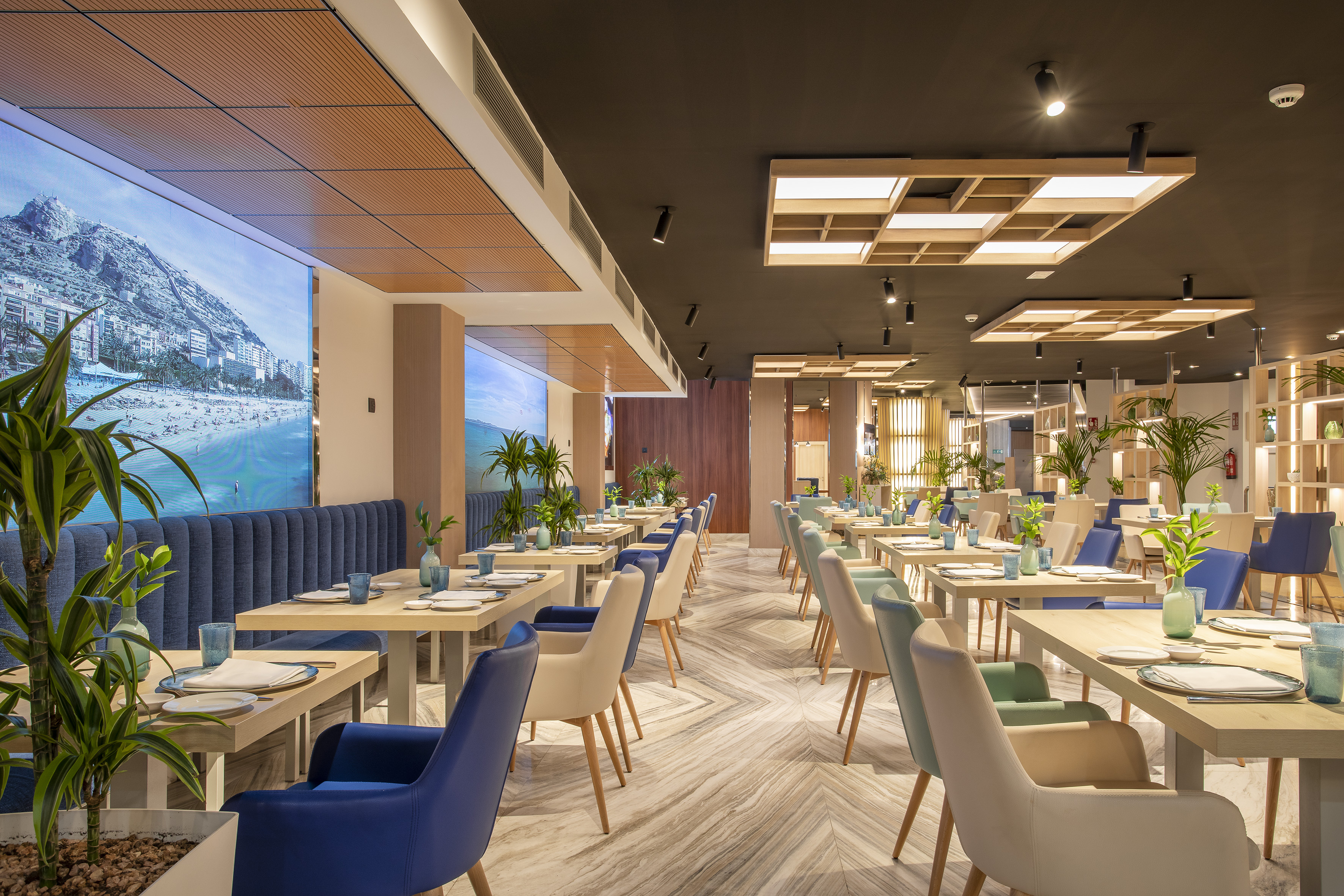 Modern restaurant dining room with beach display, blue seating, and elegant design.