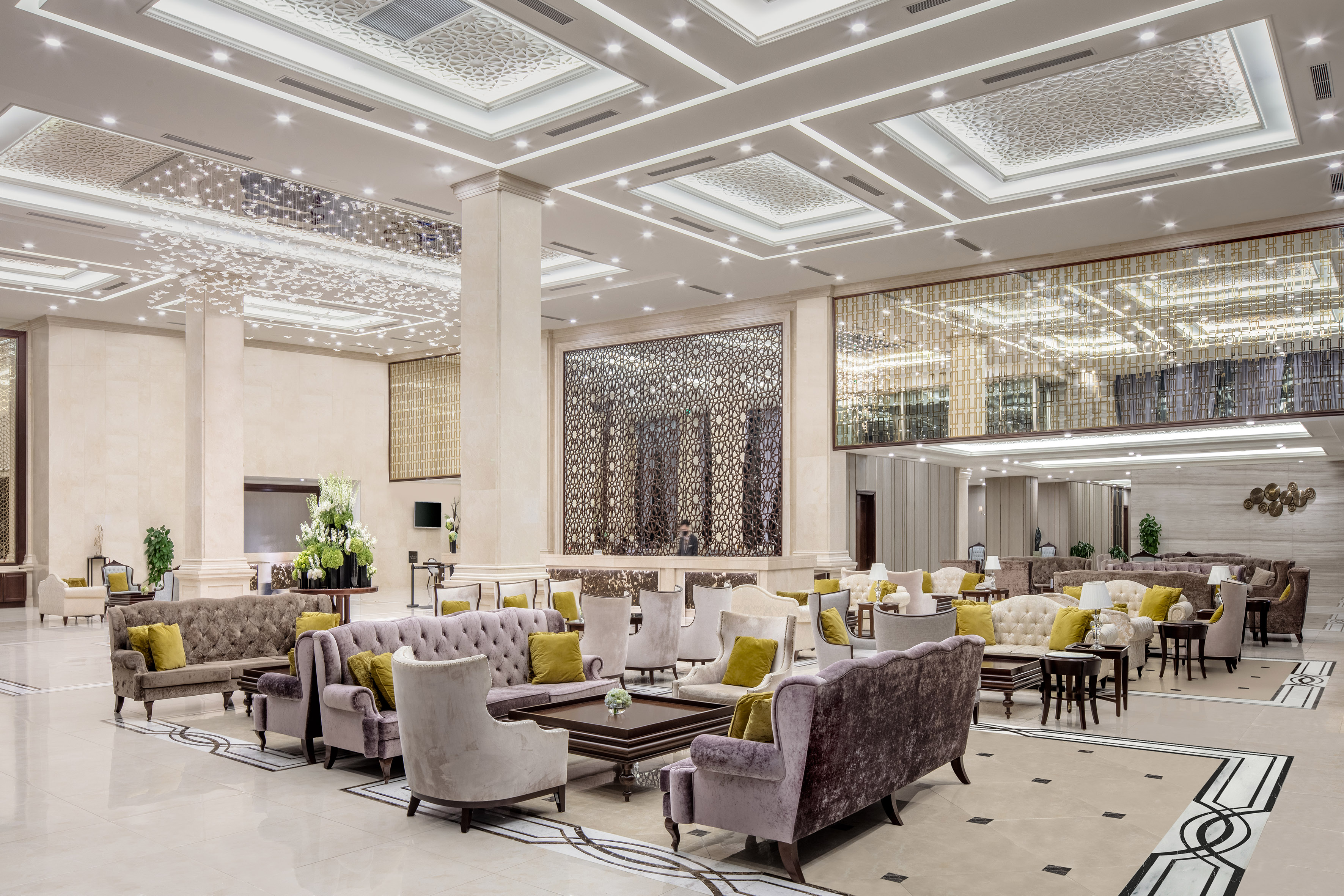 Elegant hotel lobby with patterned ceilings, plush seating, and geometric screens.
