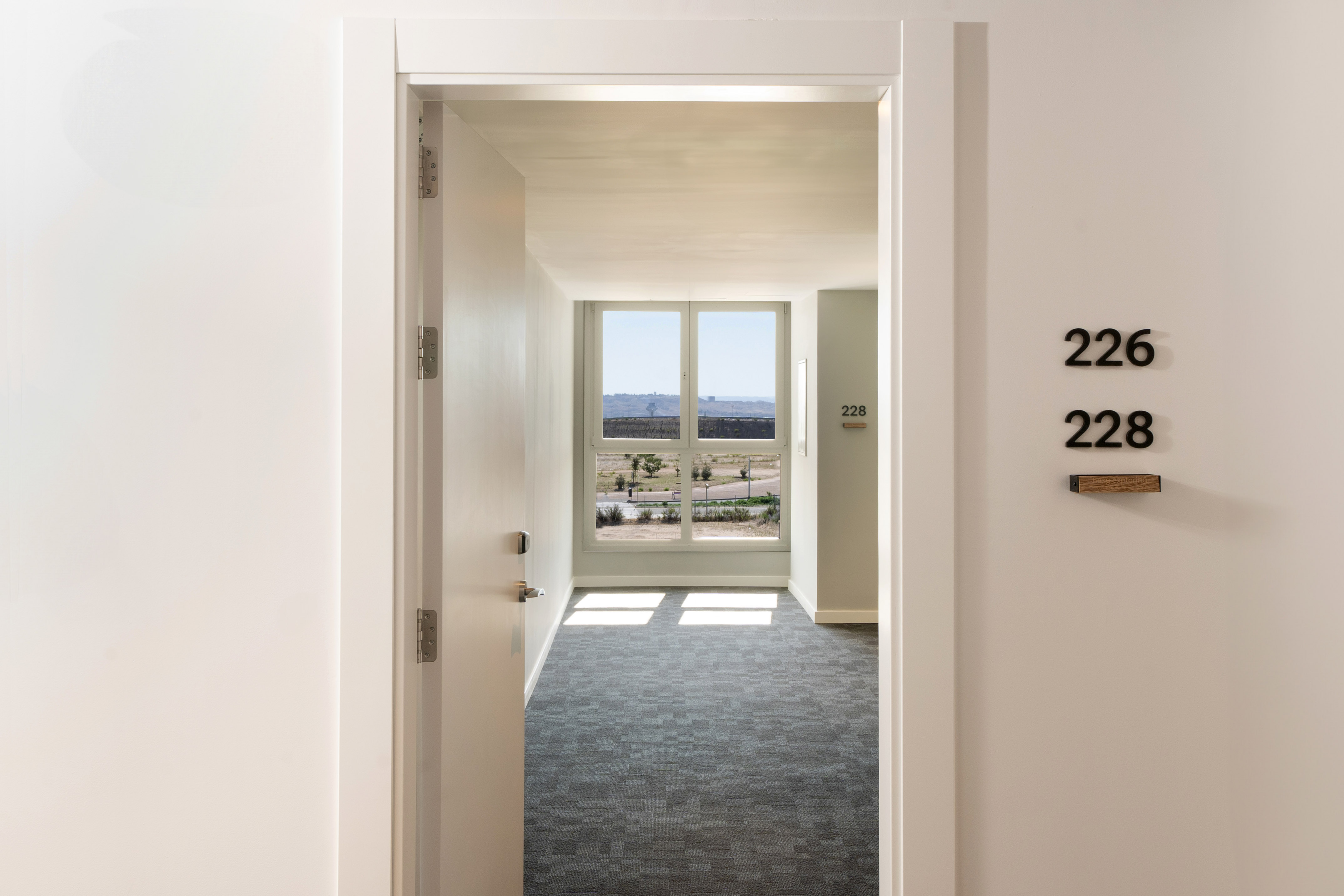 Open hotel room door 228, 226 visible, leading to a sunlit window view.