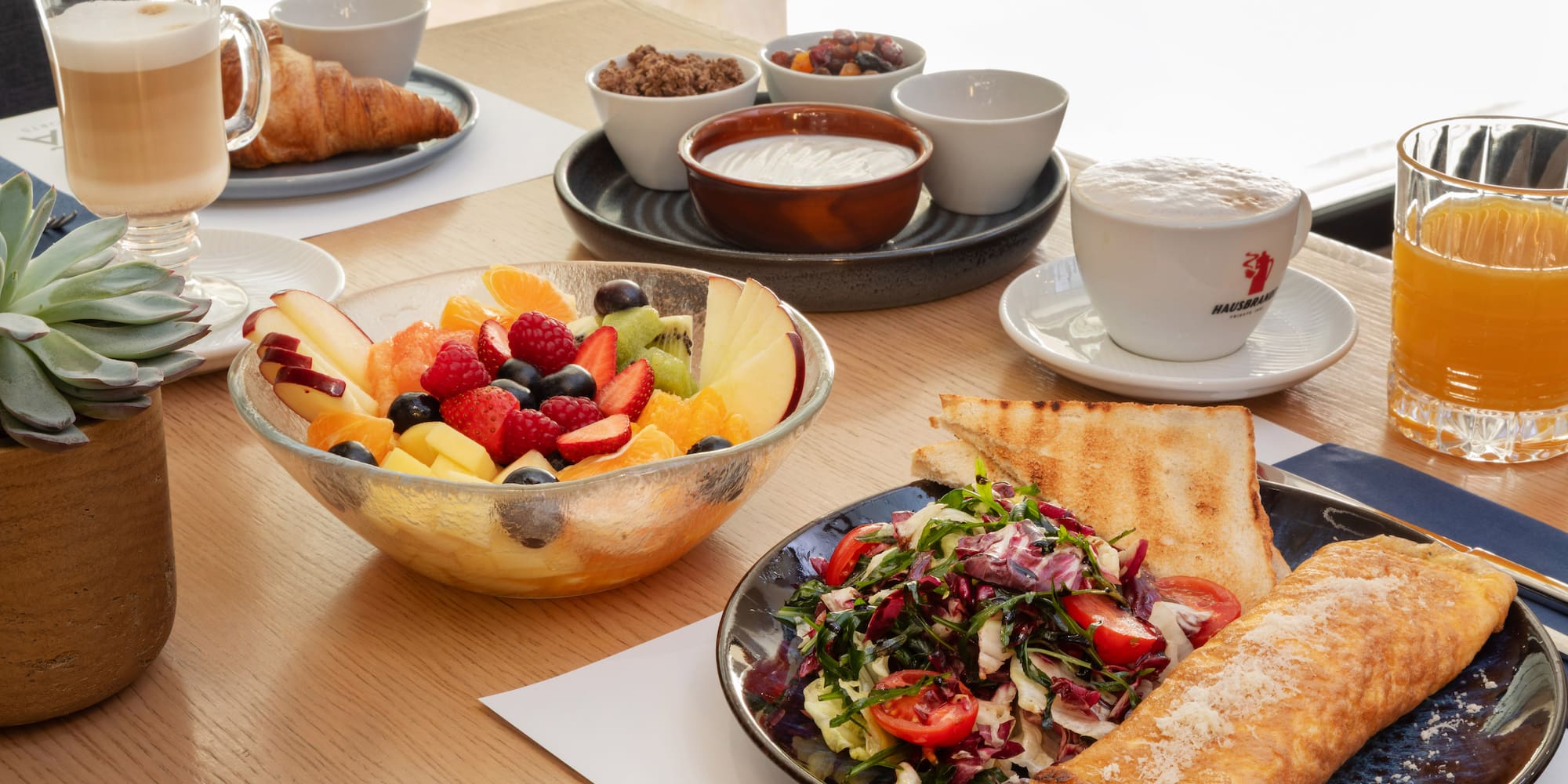 Breakfast spread: omelette, fresh fruit, croissant, coffee, and orange juice.