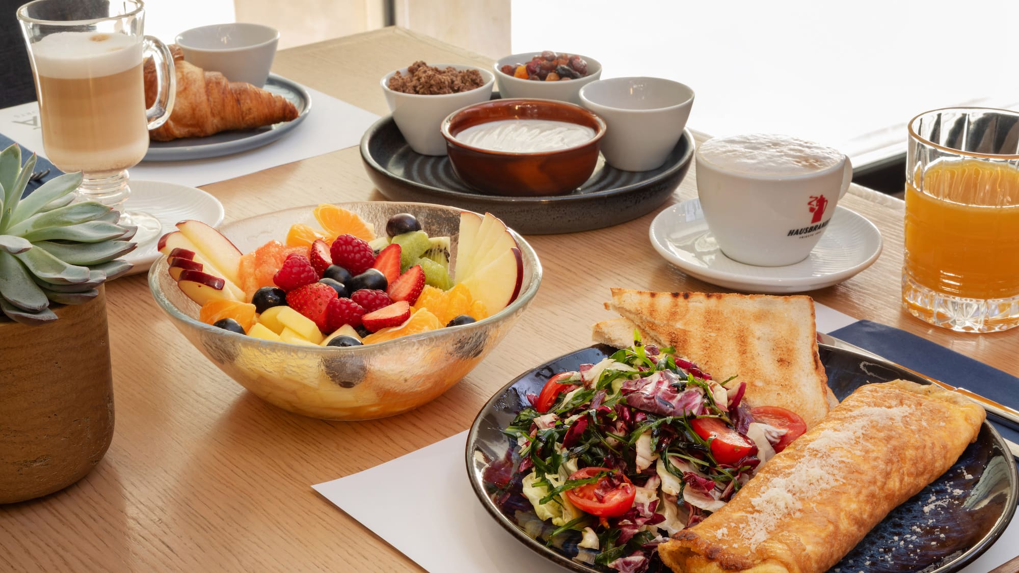 Breakfast spread: omelette, fresh fruit, croissant, coffee, and orange juice.