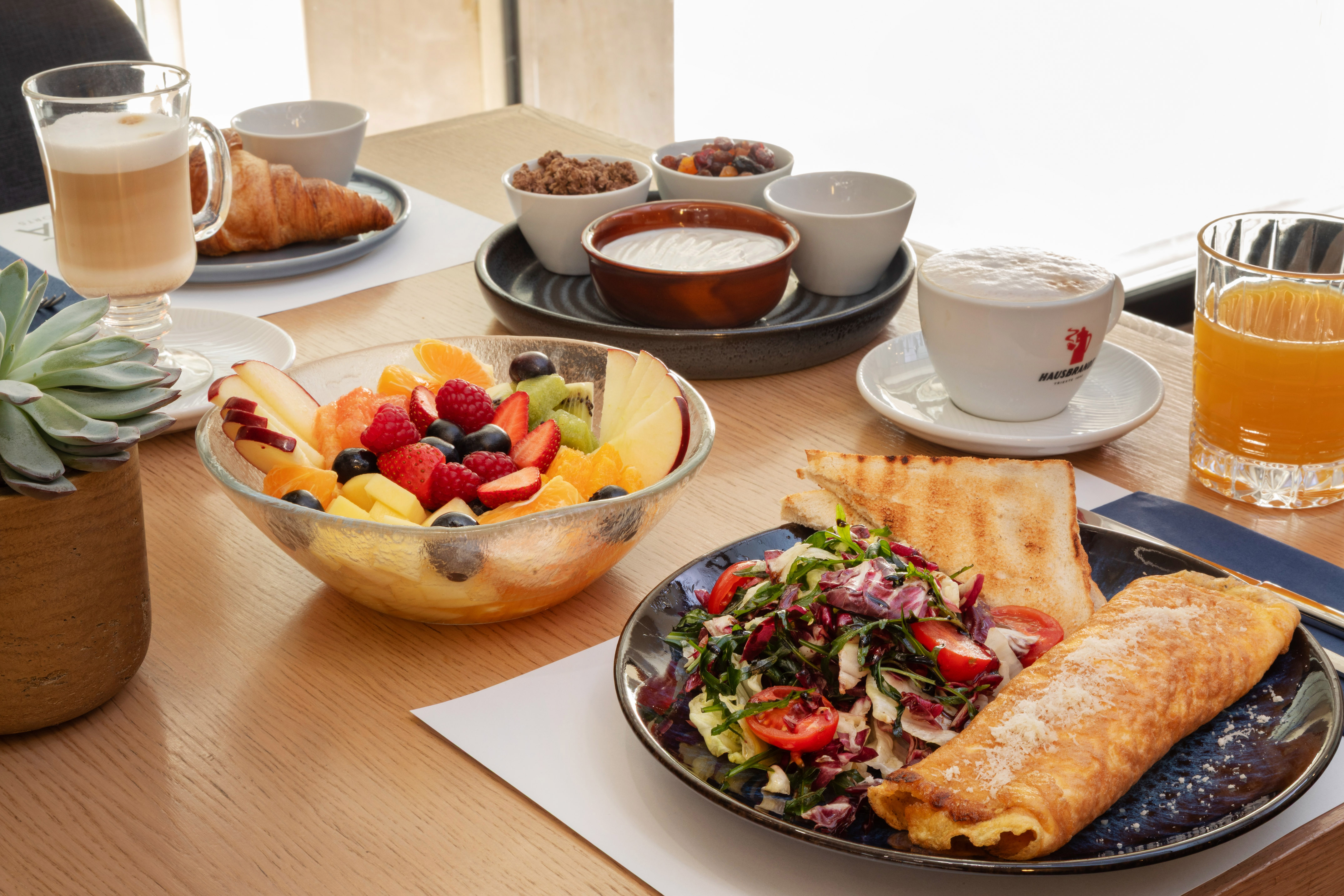 Breakfast spread: omelette, fresh fruit, croissant, coffee, and orange juice.