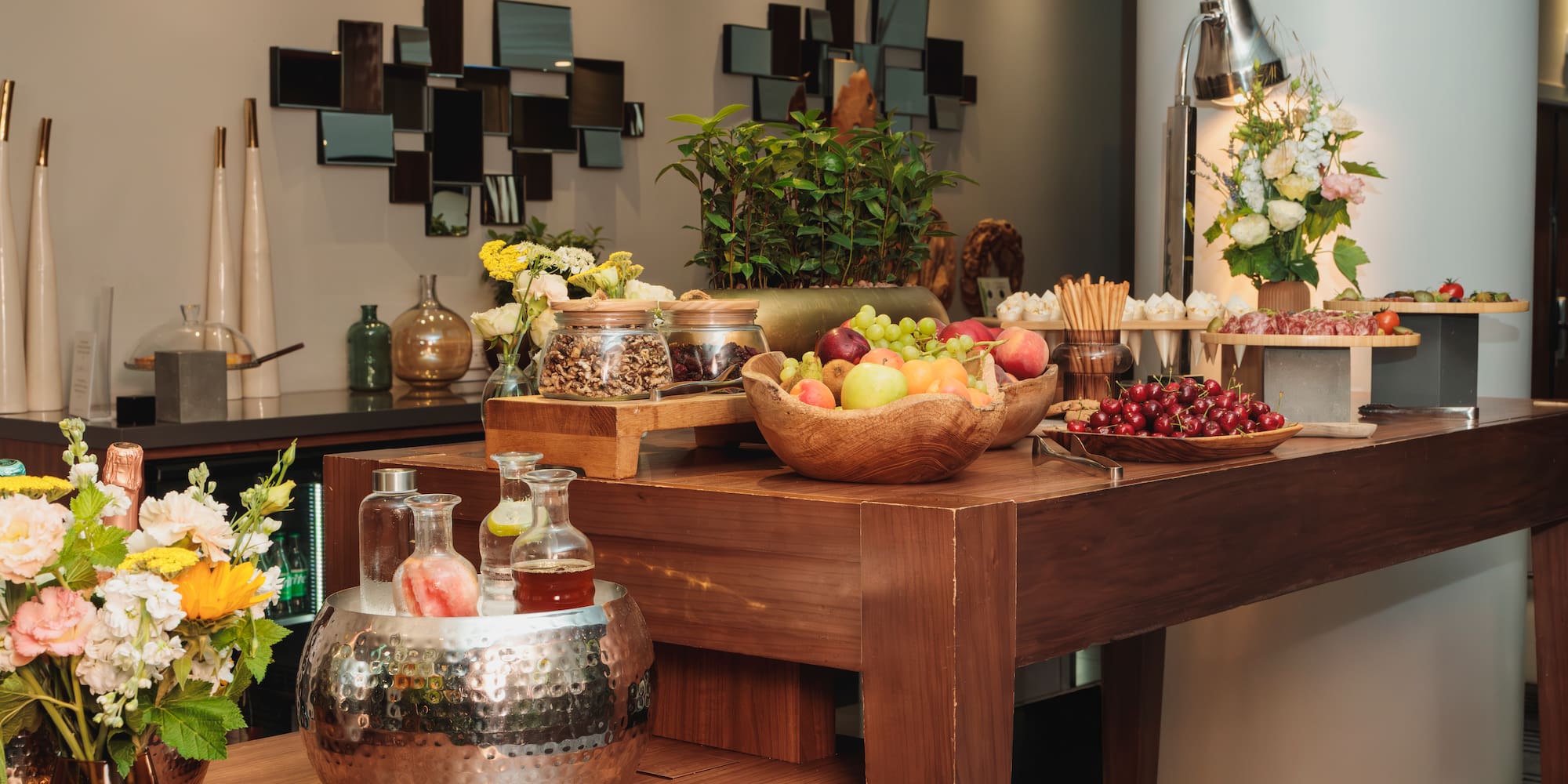 Luxury hotel buffet featuring fresh fruit, charcuterie, nuts, and bottled drinks.