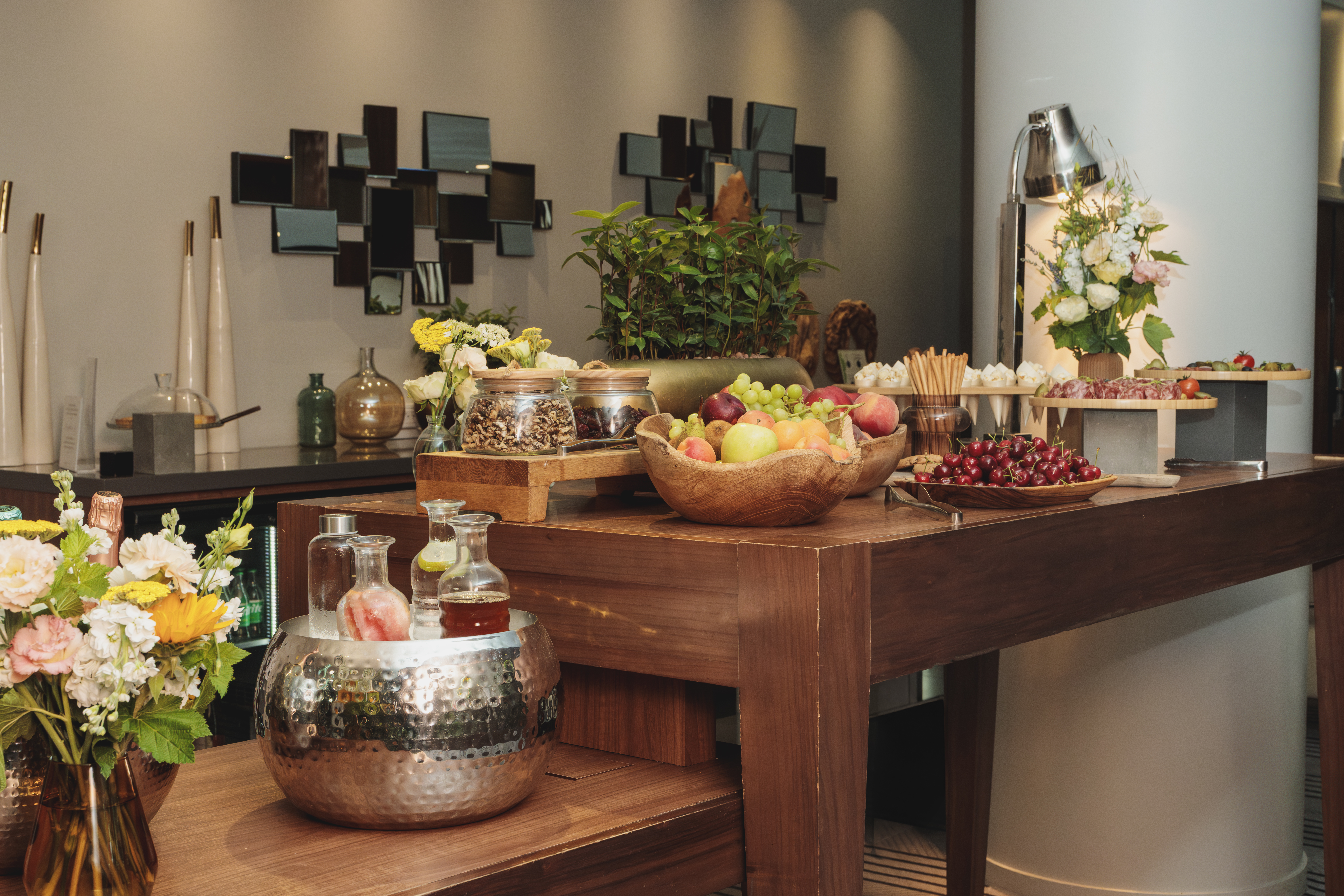 Luxury hotel buffet featuring fresh fruit, charcuterie, nuts, and bottled drinks.