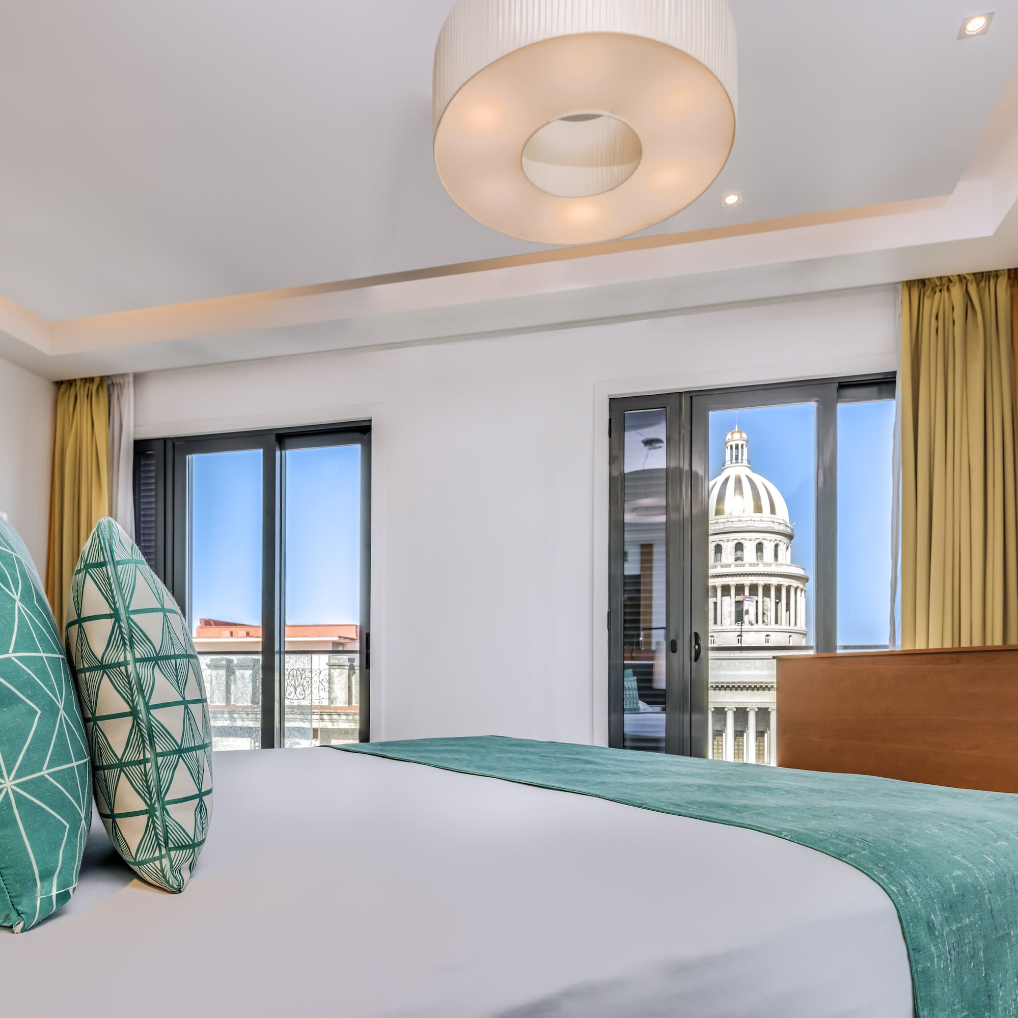 a bed with green pillows in a room with a large building in the background