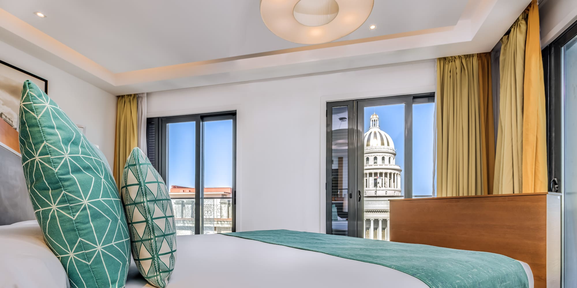 a bed with green pillows in a room with a large building in the background