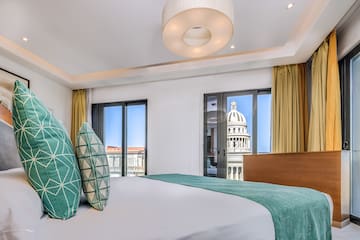 a bed with green pillows in a room with a large building in the background