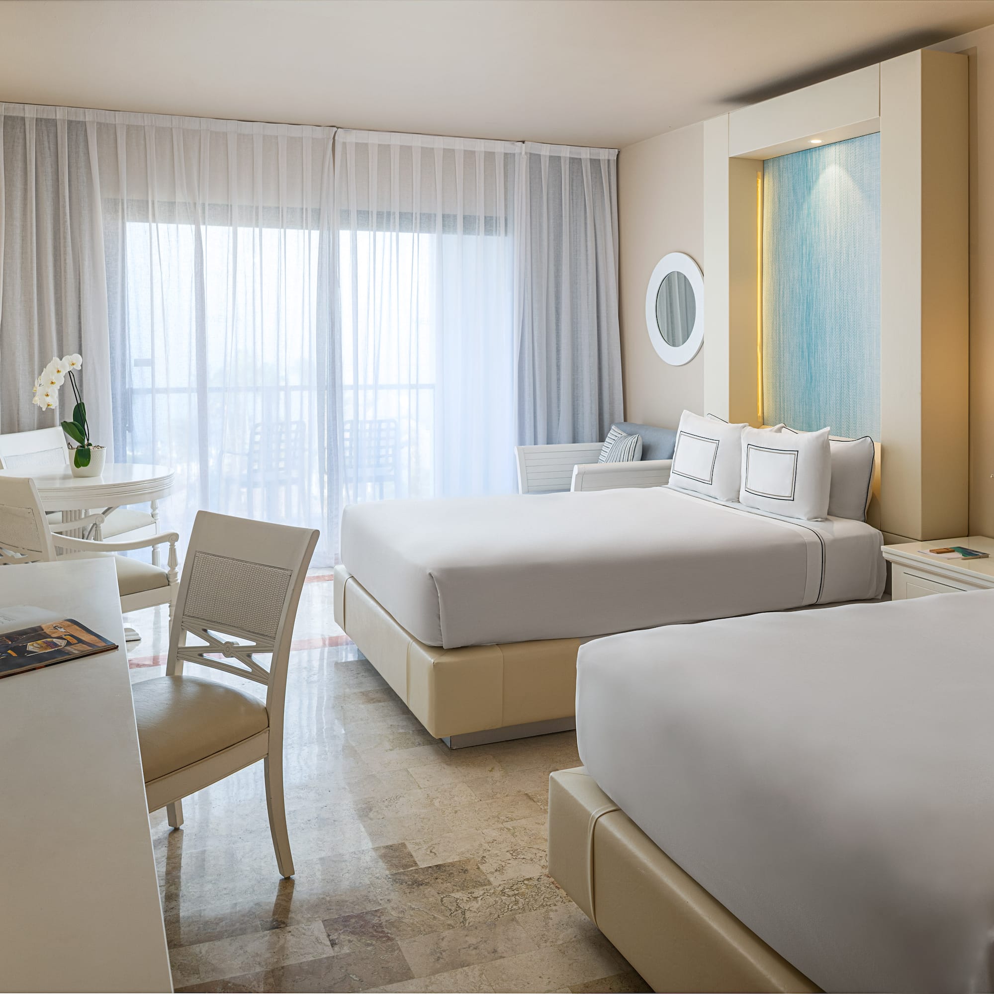 Spacious, bright hotel room featuring two queen beds and a balcony.