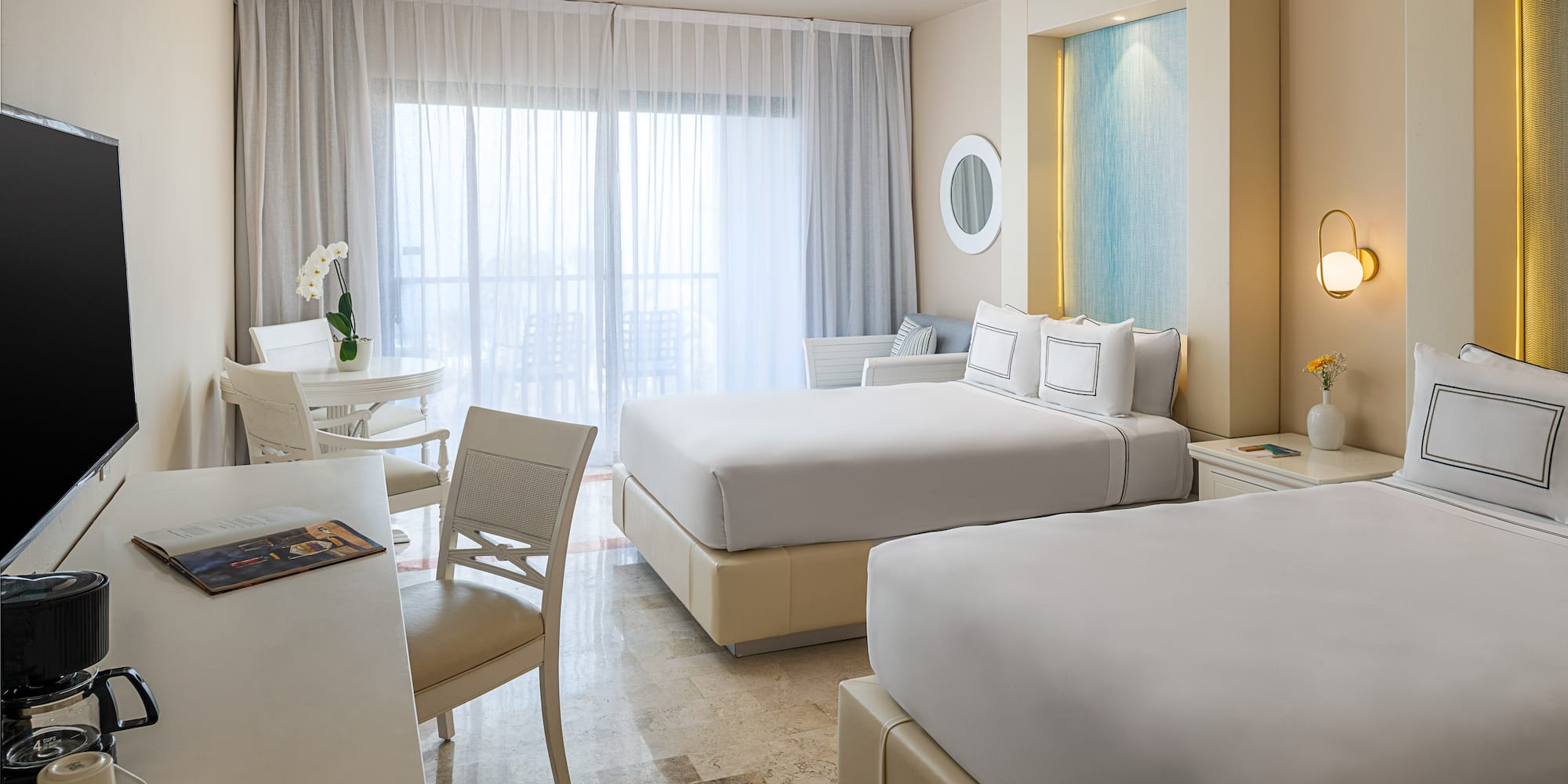 Spacious, bright hotel room featuring two queen beds and a balcony.