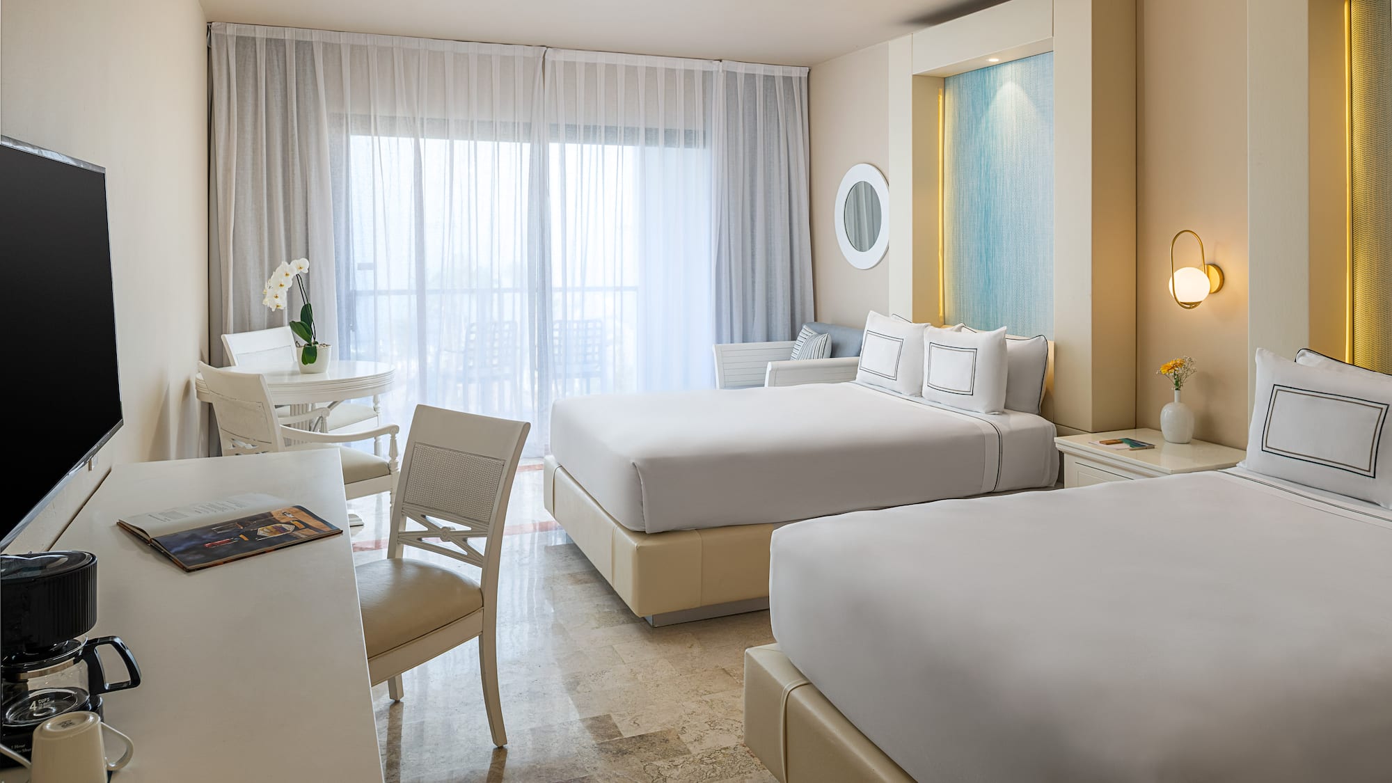 Spacious, bright hotel room featuring two queen beds and a balcony.