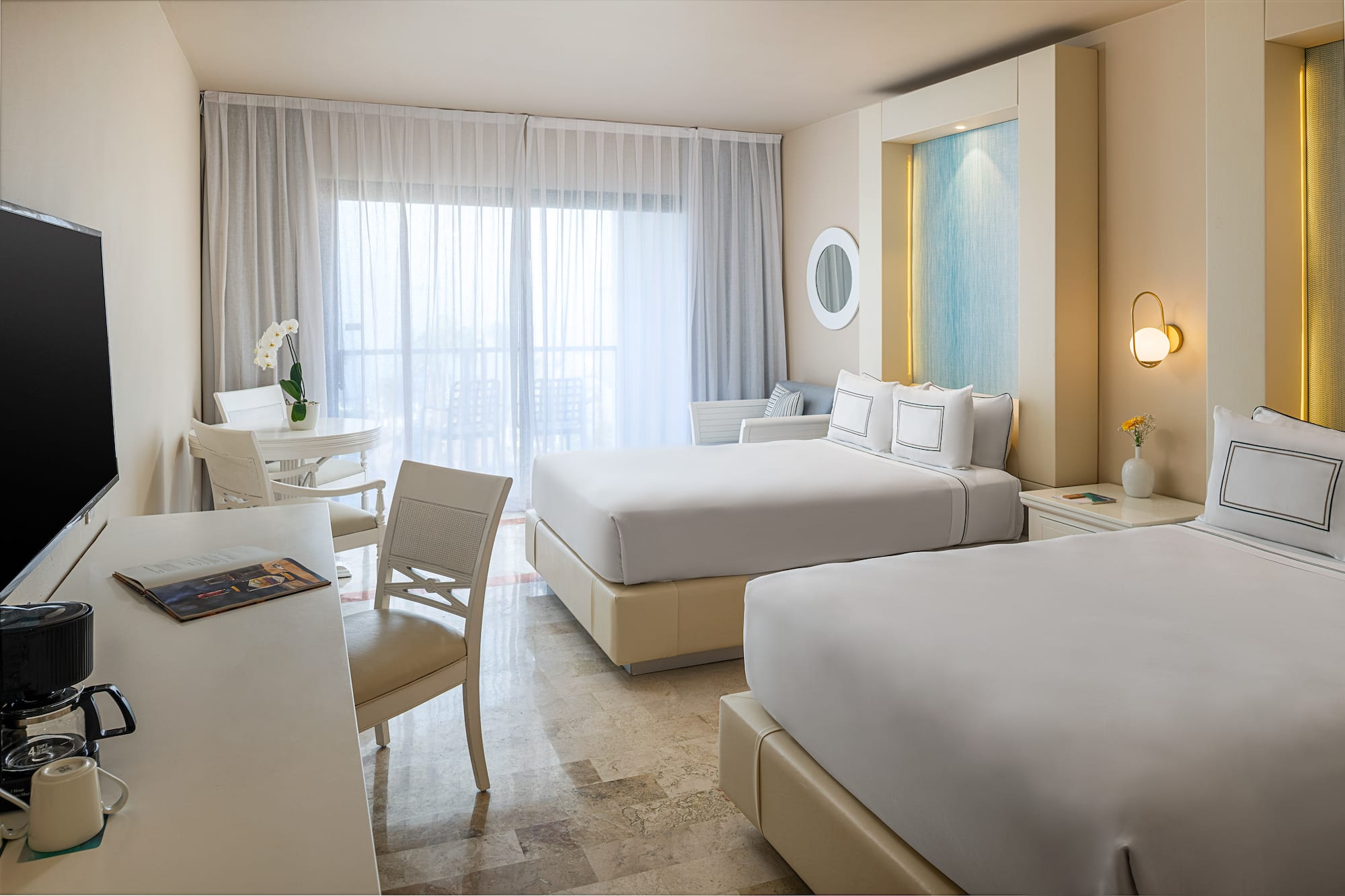 Modern hotel room with two queen beds, balcony, and sitting area.
