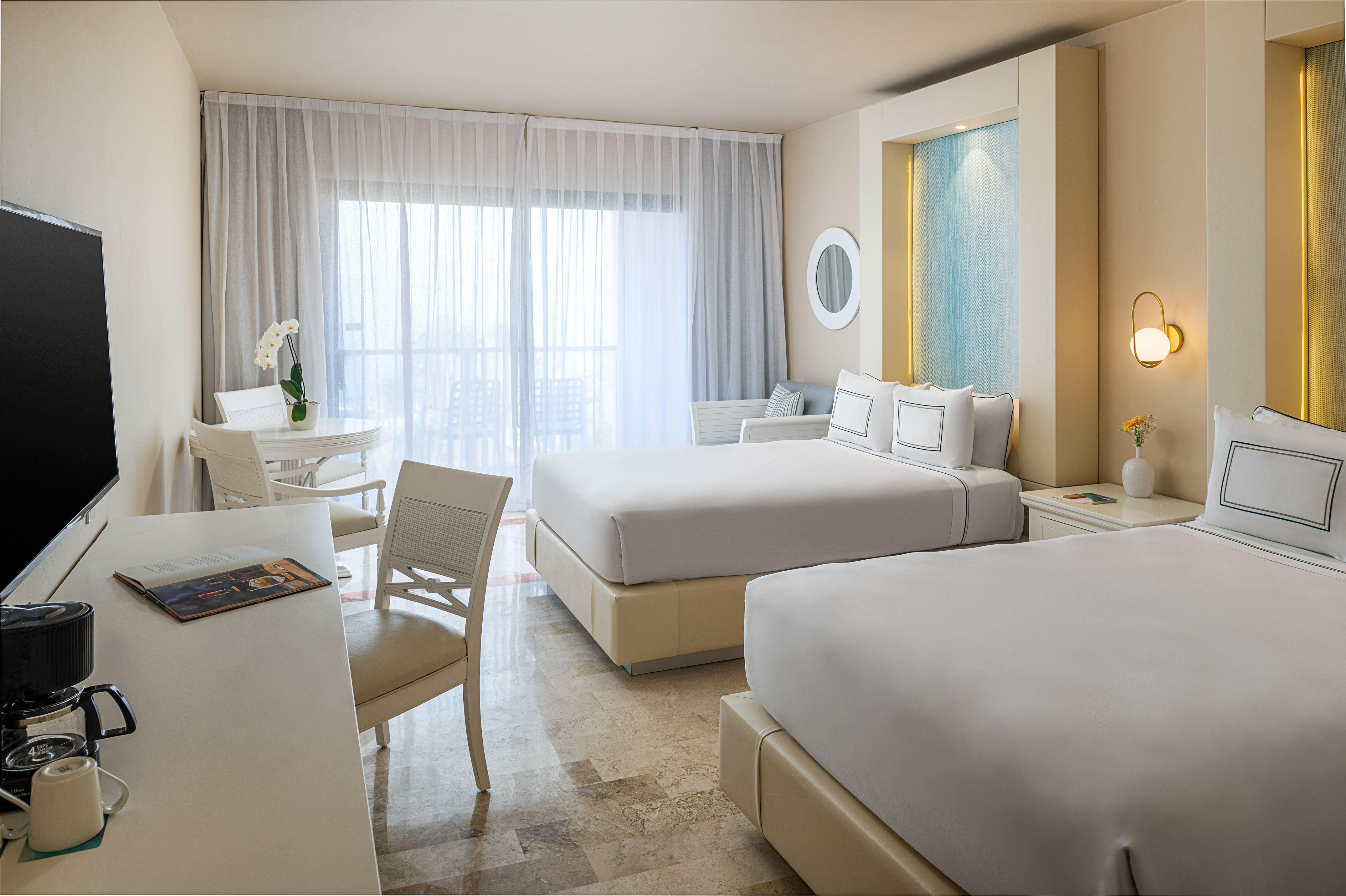 Modern hotel room with two queen beds, balcony, and sitting area.