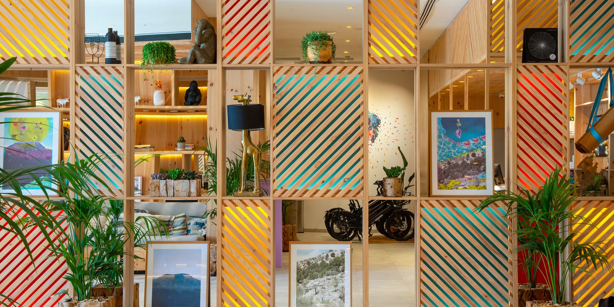 a room with a mirror wall and shelves with plants and a lamp