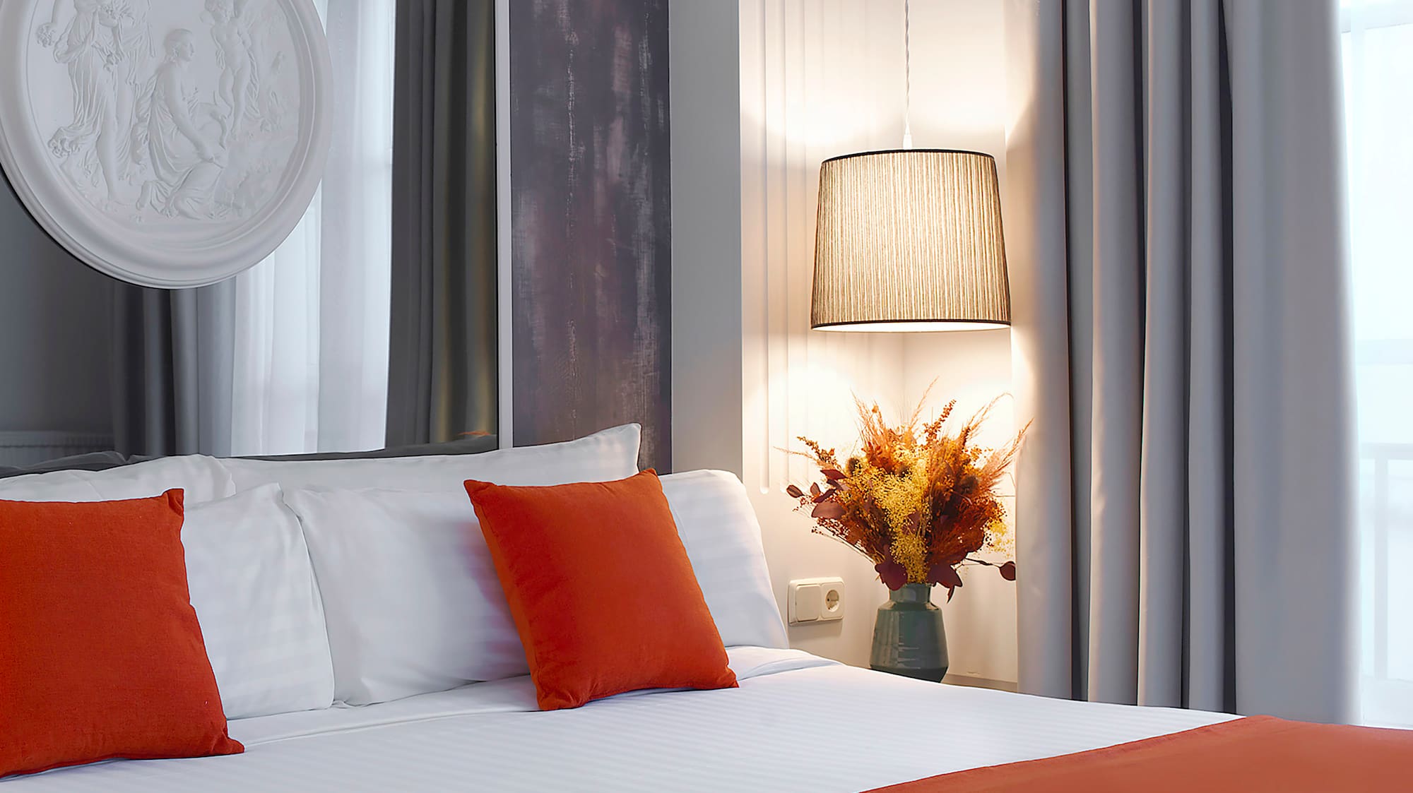 a bed with orange pillows and a lamp