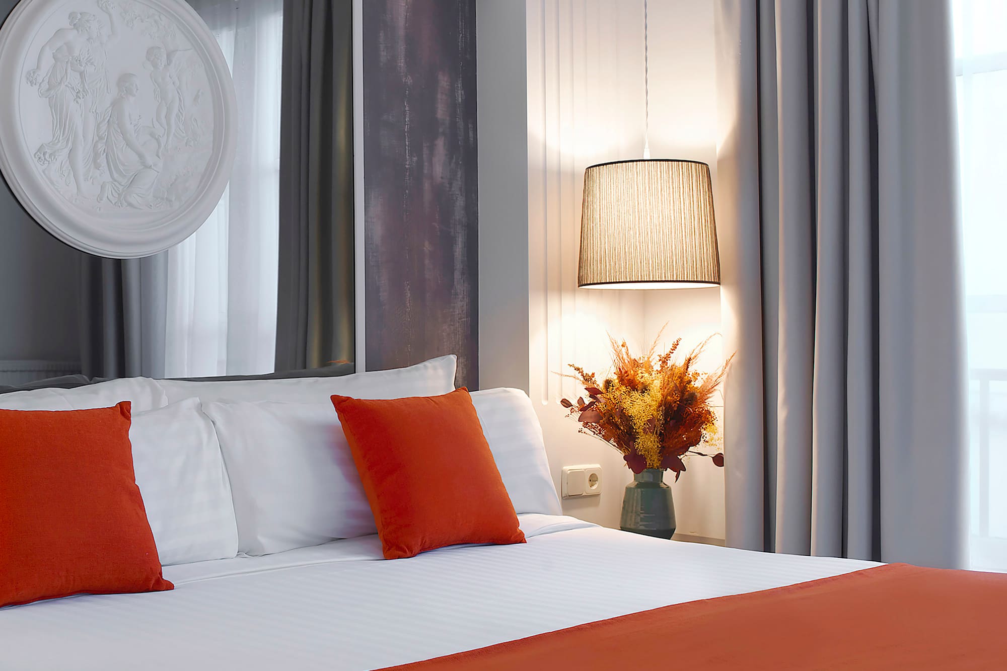 a bed with orange pillows and a lamp