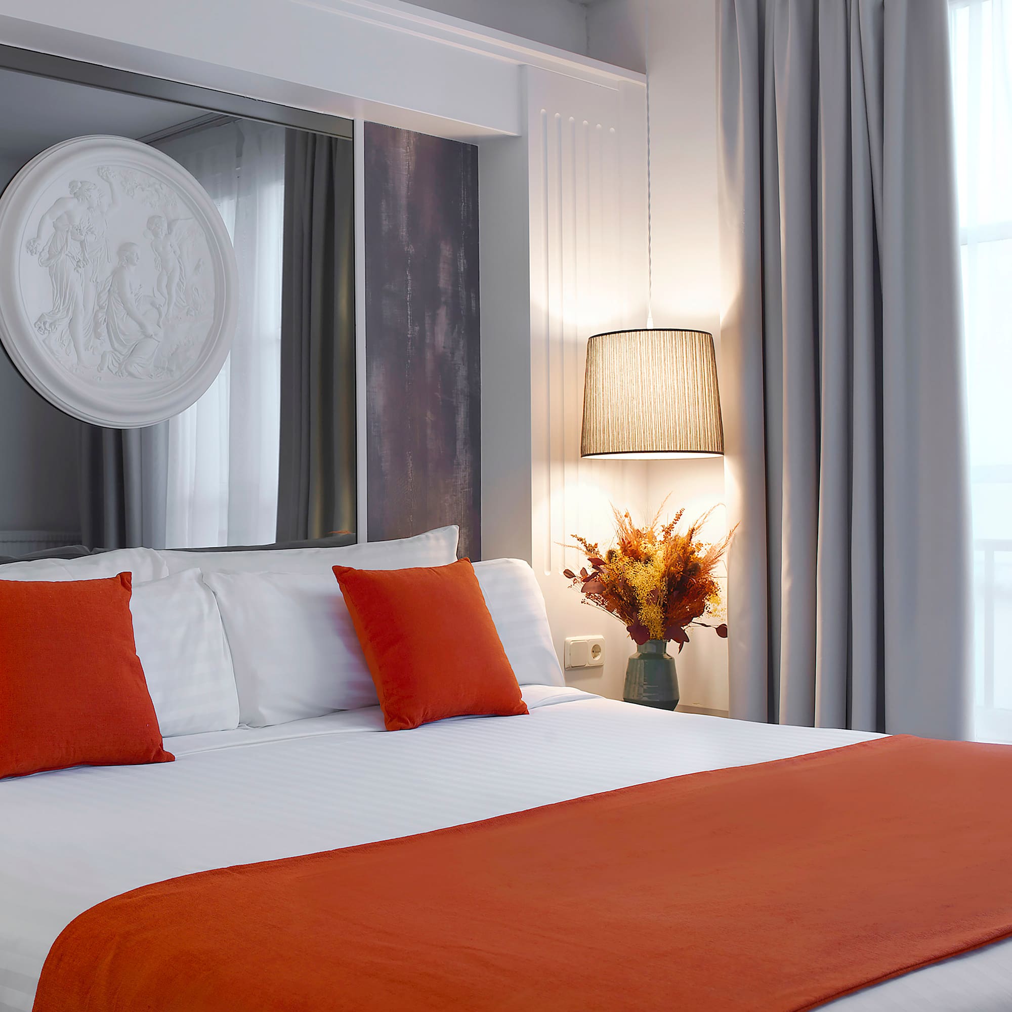 a bed with orange pillows and a lamp