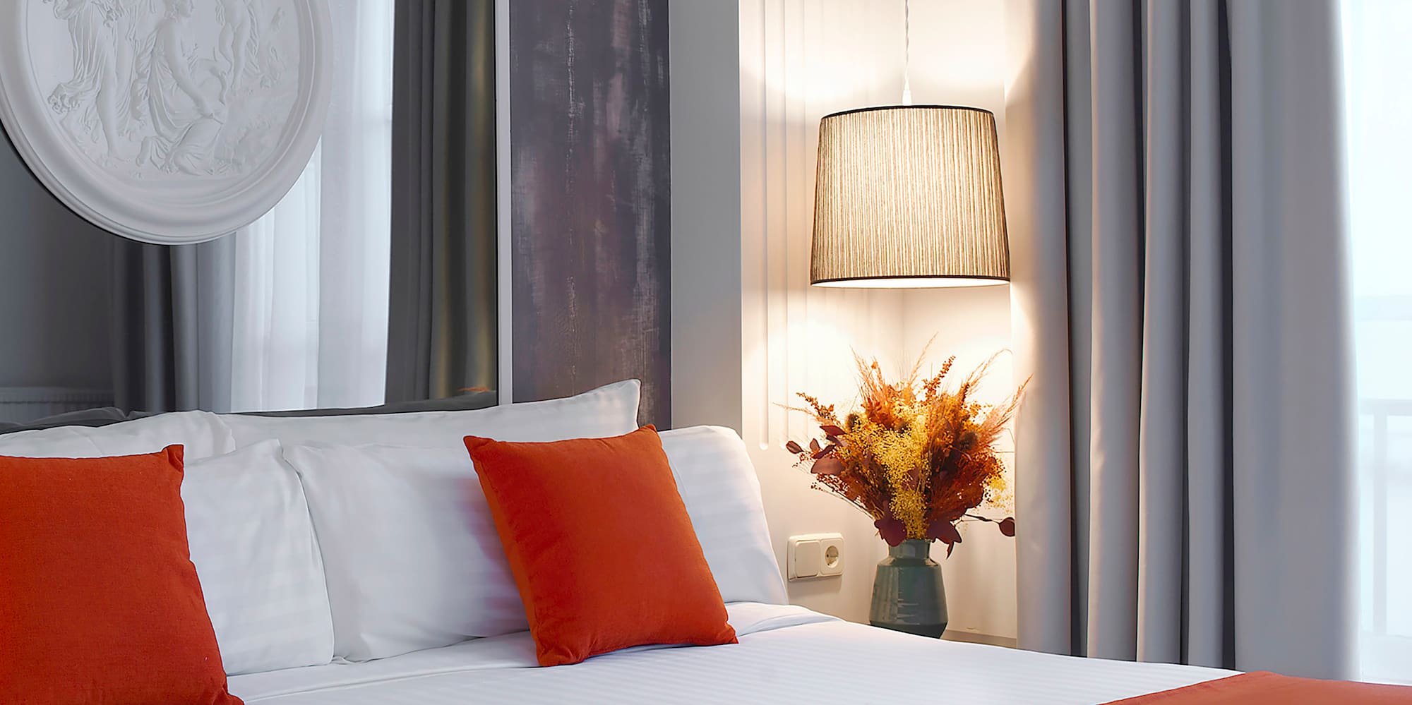 a bed with orange pillows and a lamp