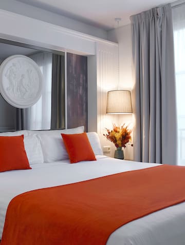 a bed with orange pillows and a lamp