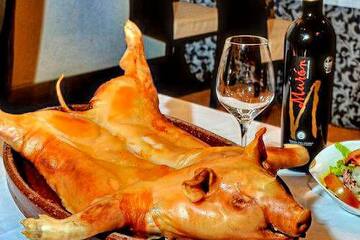 a pig's head on a plate with a bottle of wine