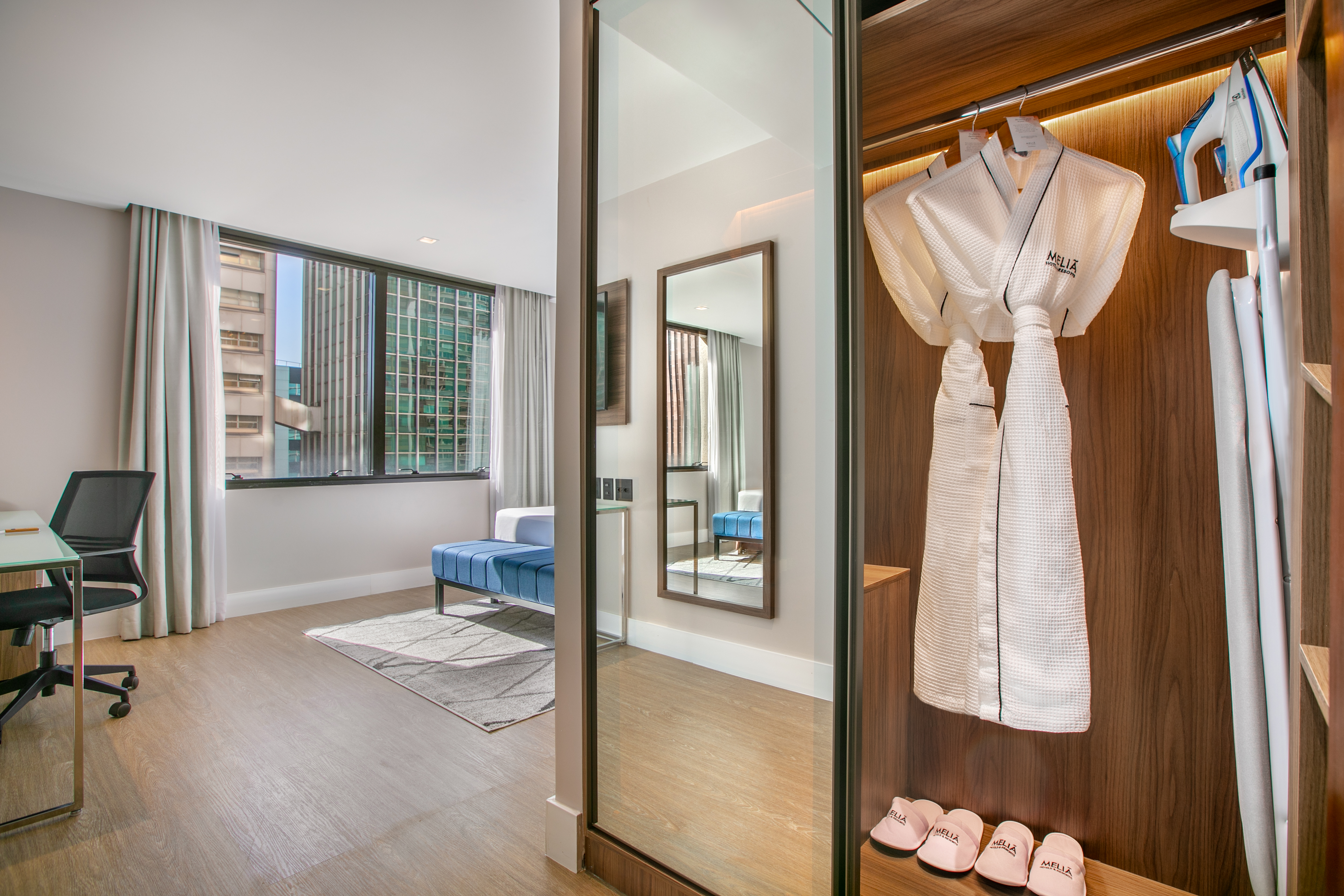 Meliá hotel room closet: robes, iron, slippers. Plus city view & desk.