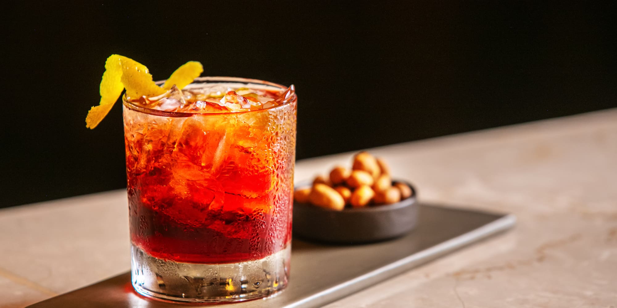 a glass of liquid with ice and a lemon wedge