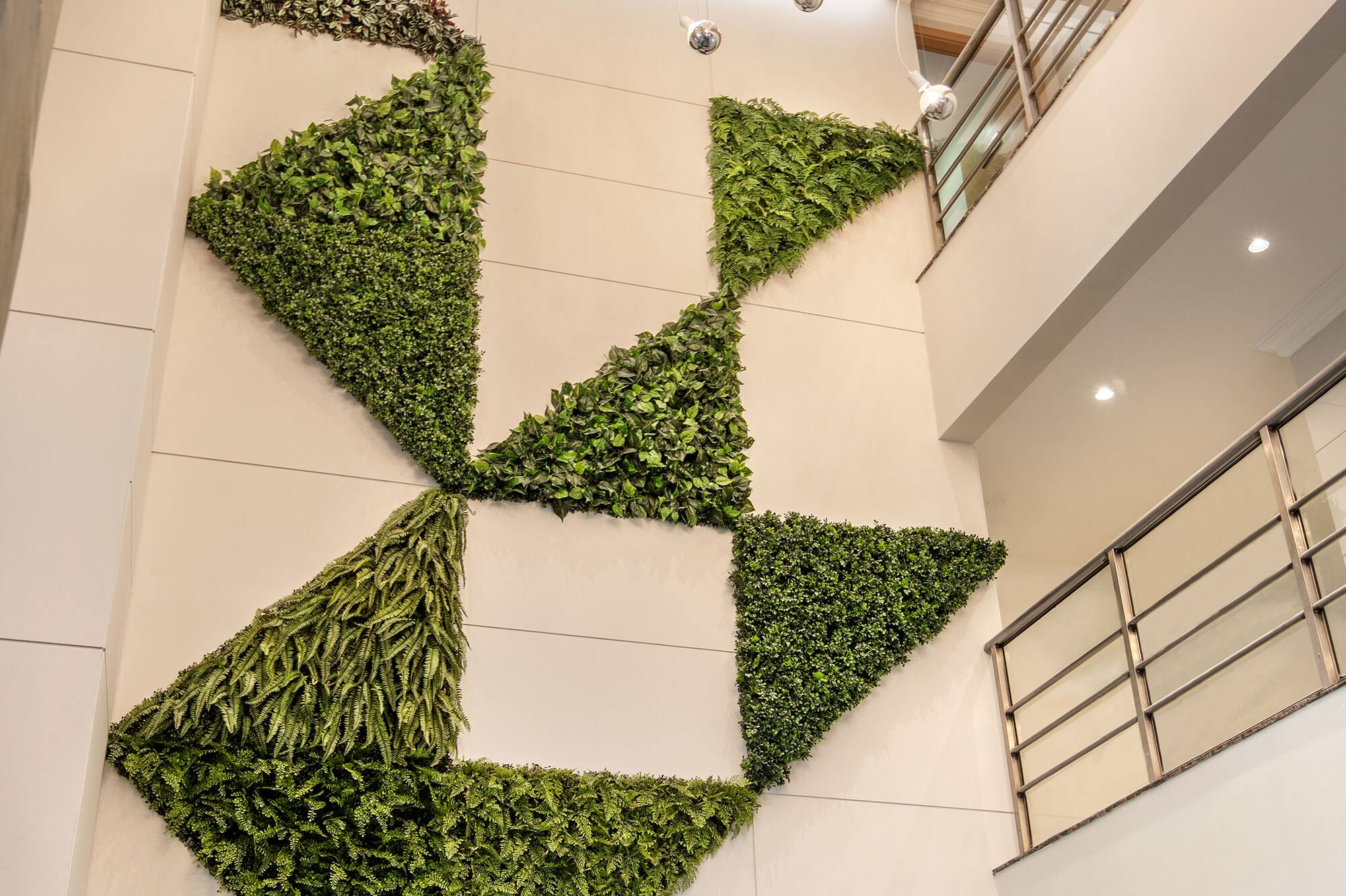 Modern geometric living wall on white interior, lit by pendant lights.