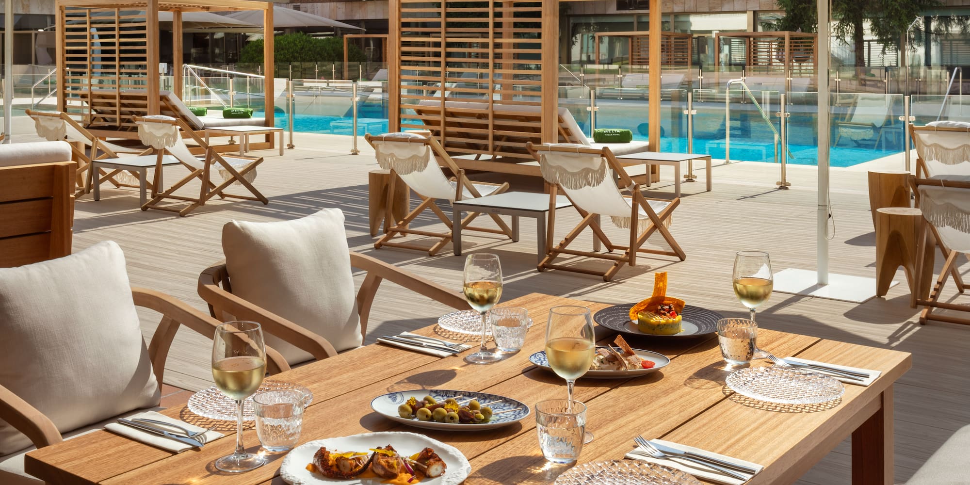 a table with food on it and chairs and a pool in the background