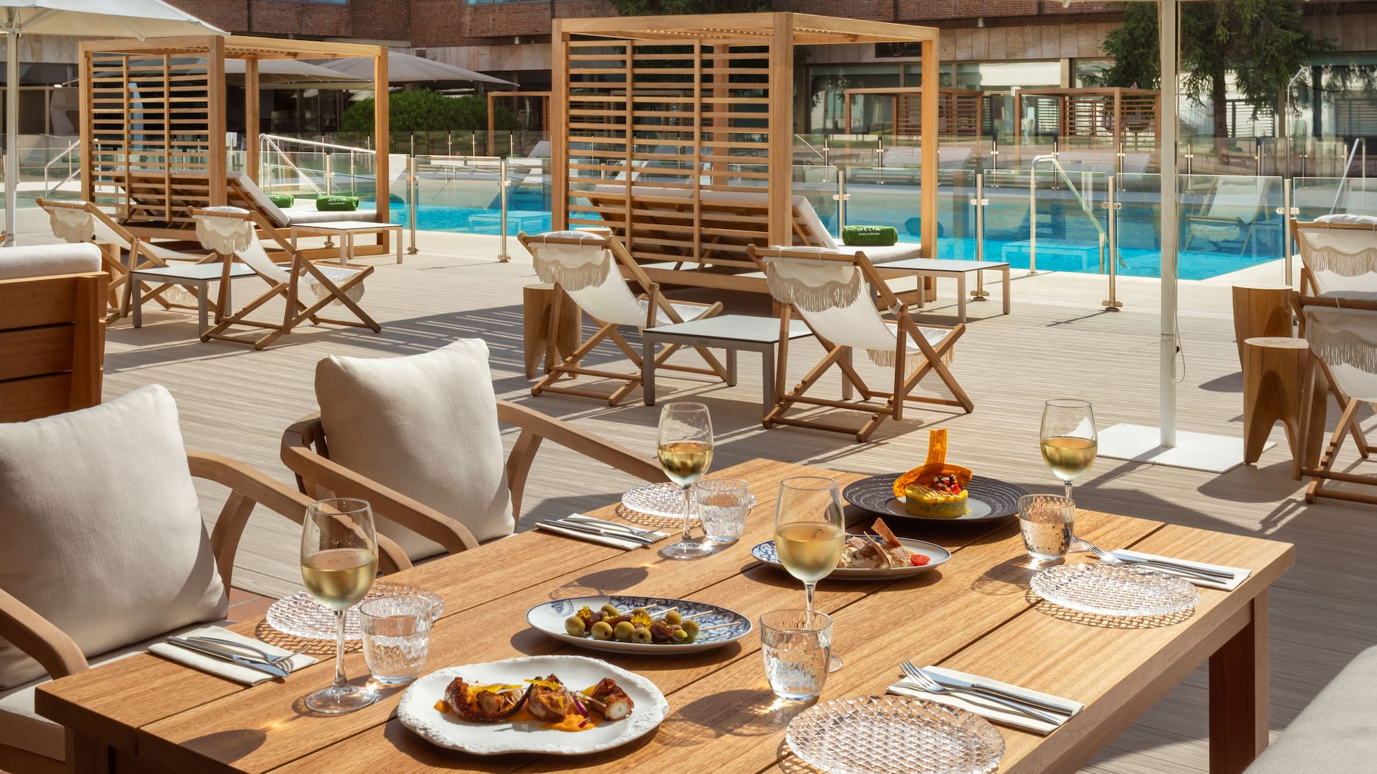 a table with food on it and chairs and a pool in the background
