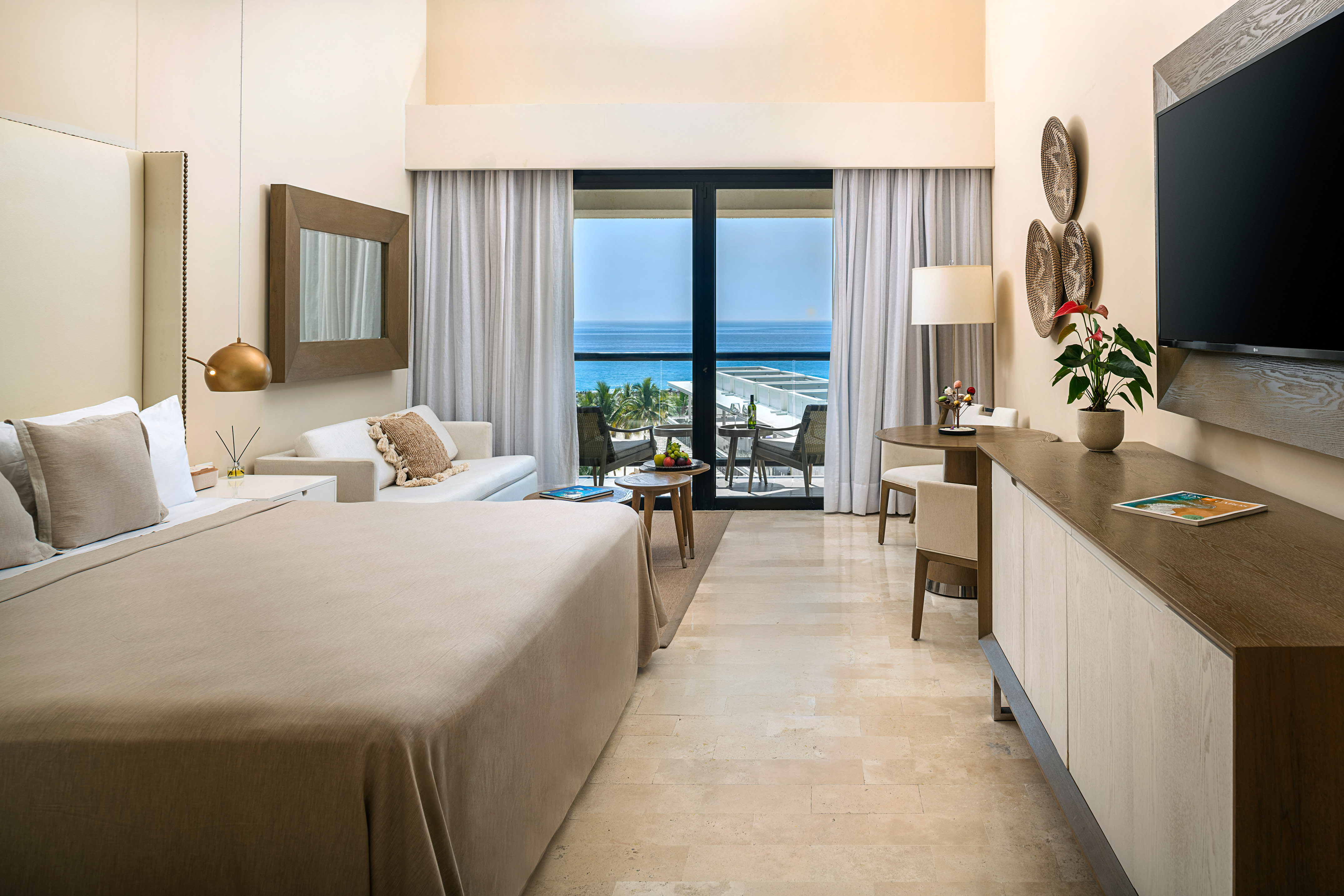 Luxury hotel room with ocean view balcony, king bed, and modern decor.
