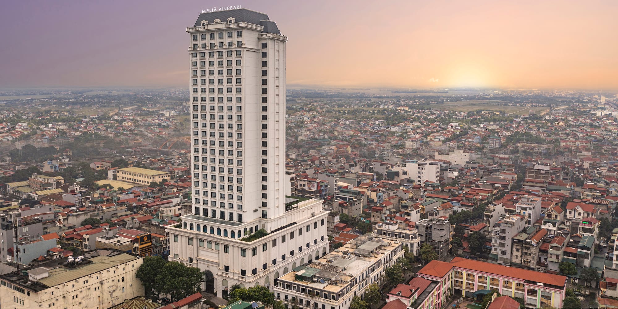 a tall white building with many windows and a city in the background
