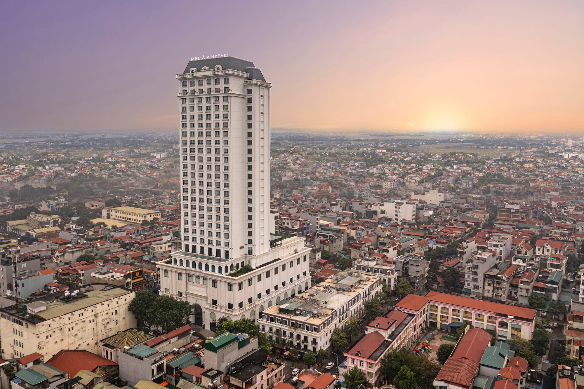 Meliã Vinpearl high-rise hotel overlooks a hazy Vietnamese cityscape at sunset.