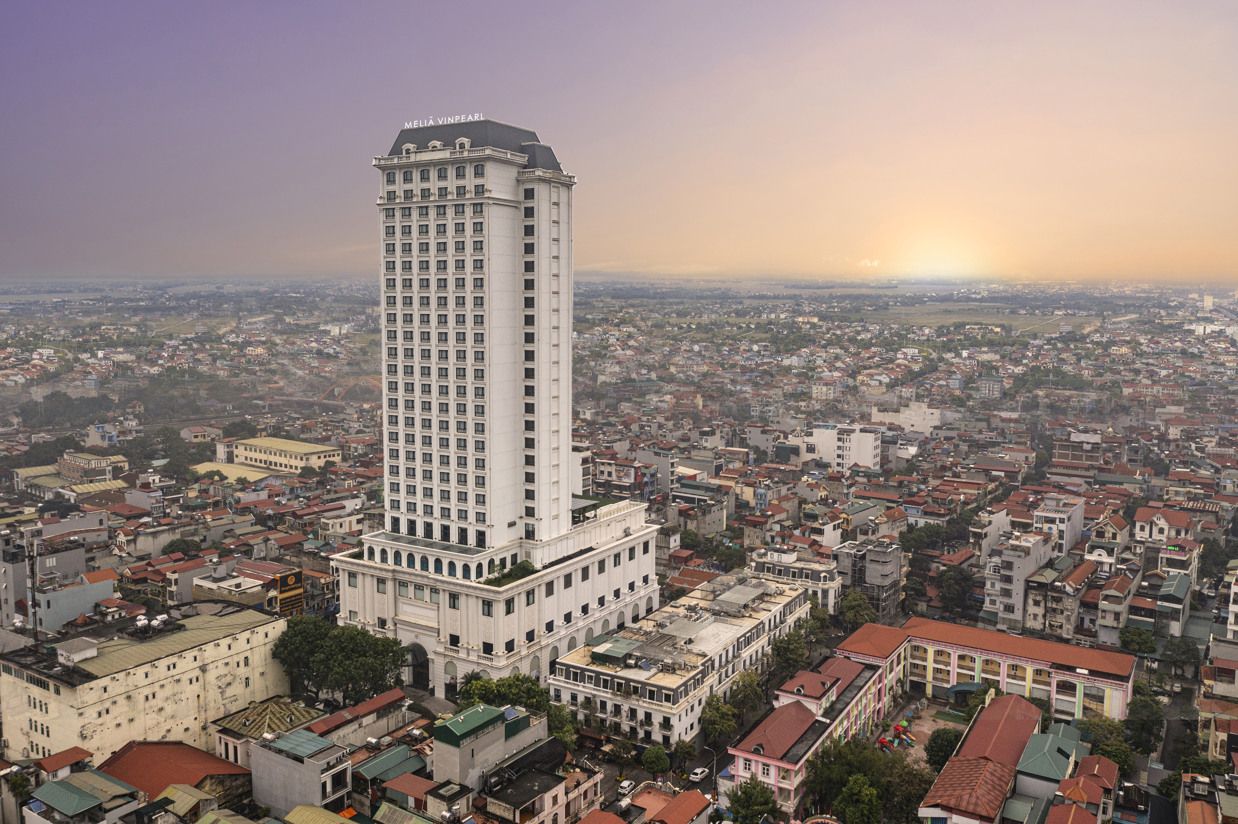 a tall white building with many windows and a city in the background