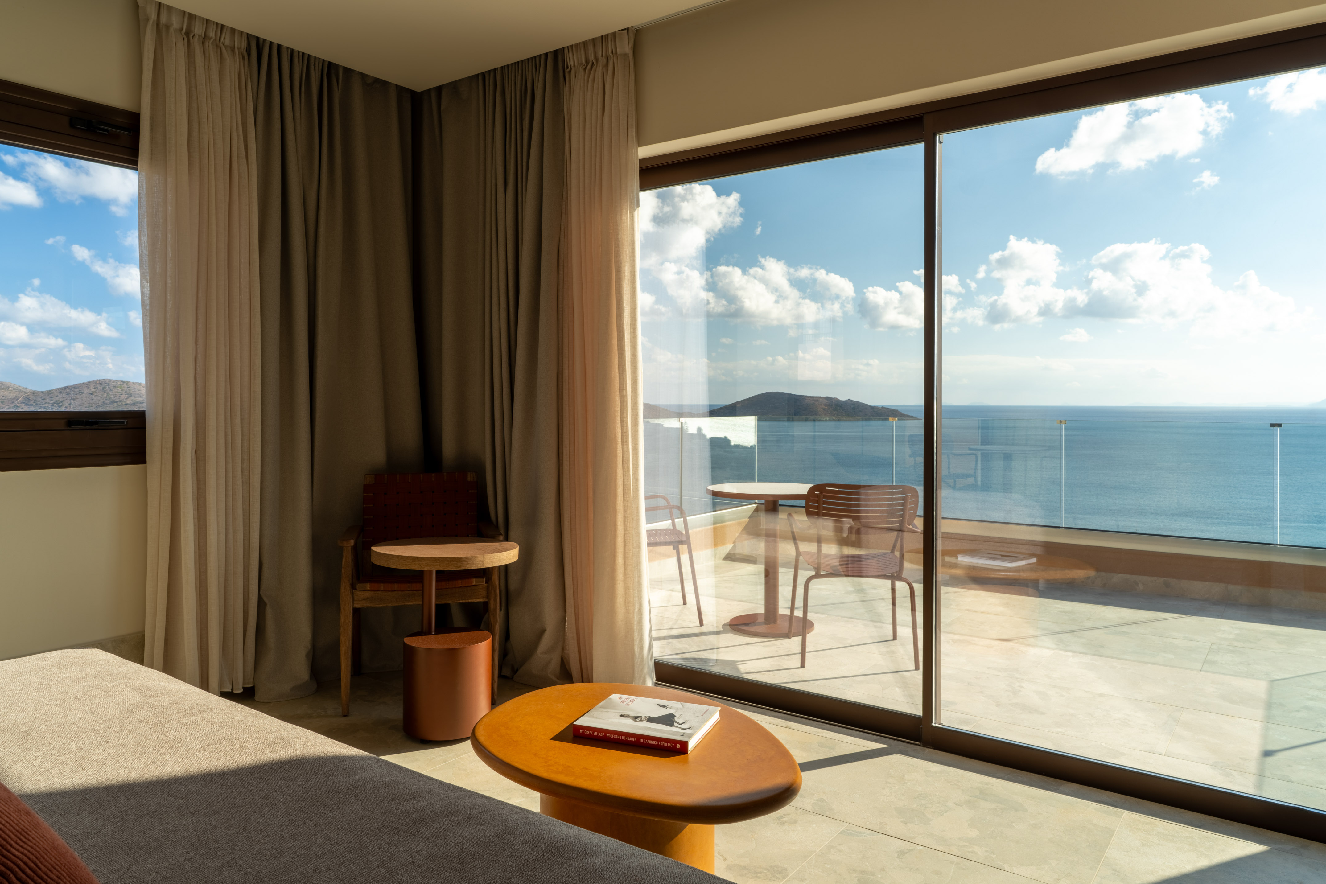 Modern hotel room with sofa, coffee table, and balcony with ocean views.