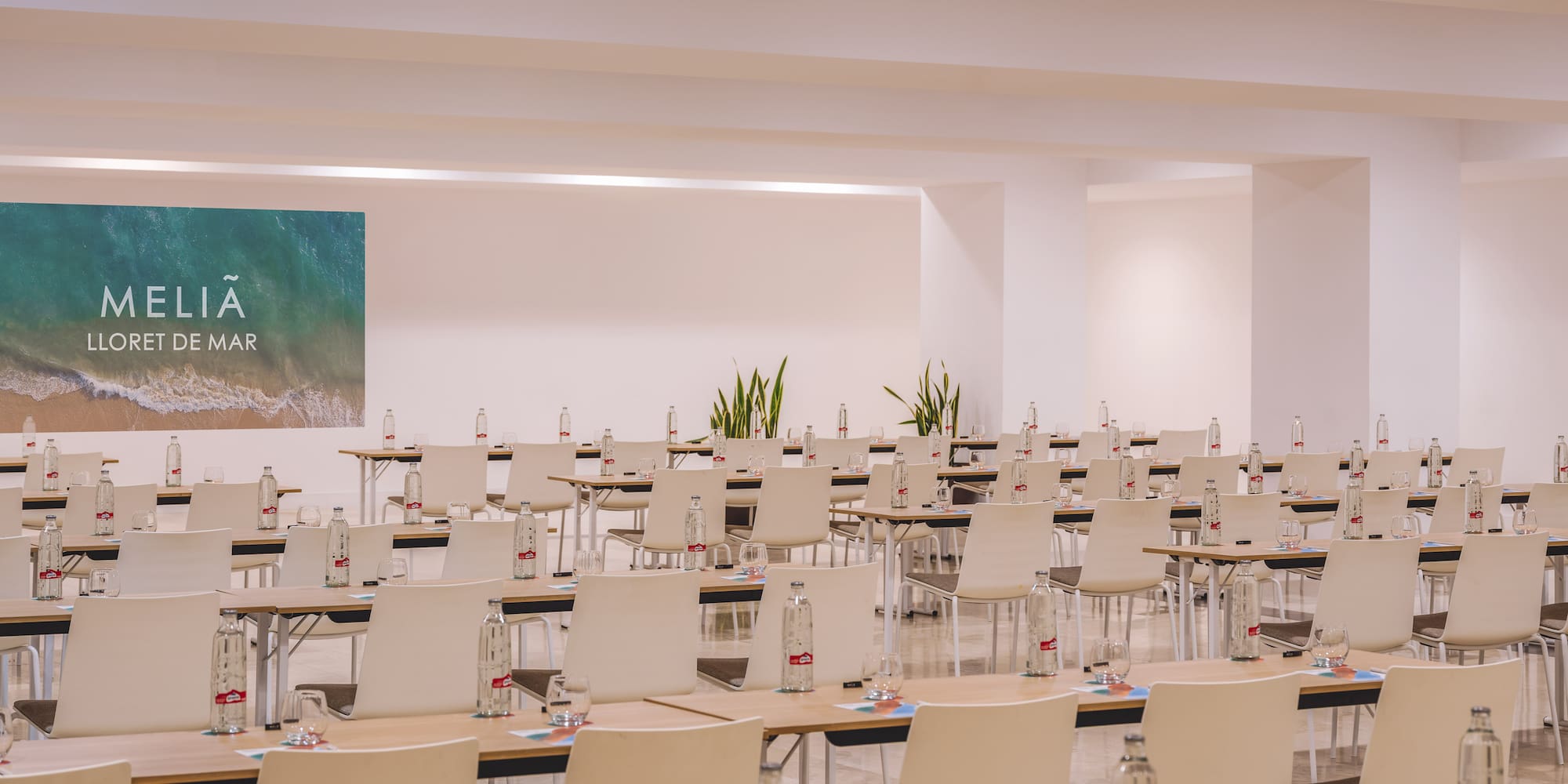 Meliá Lloret de Mar event room setup with tables, chairs, and bottled water.