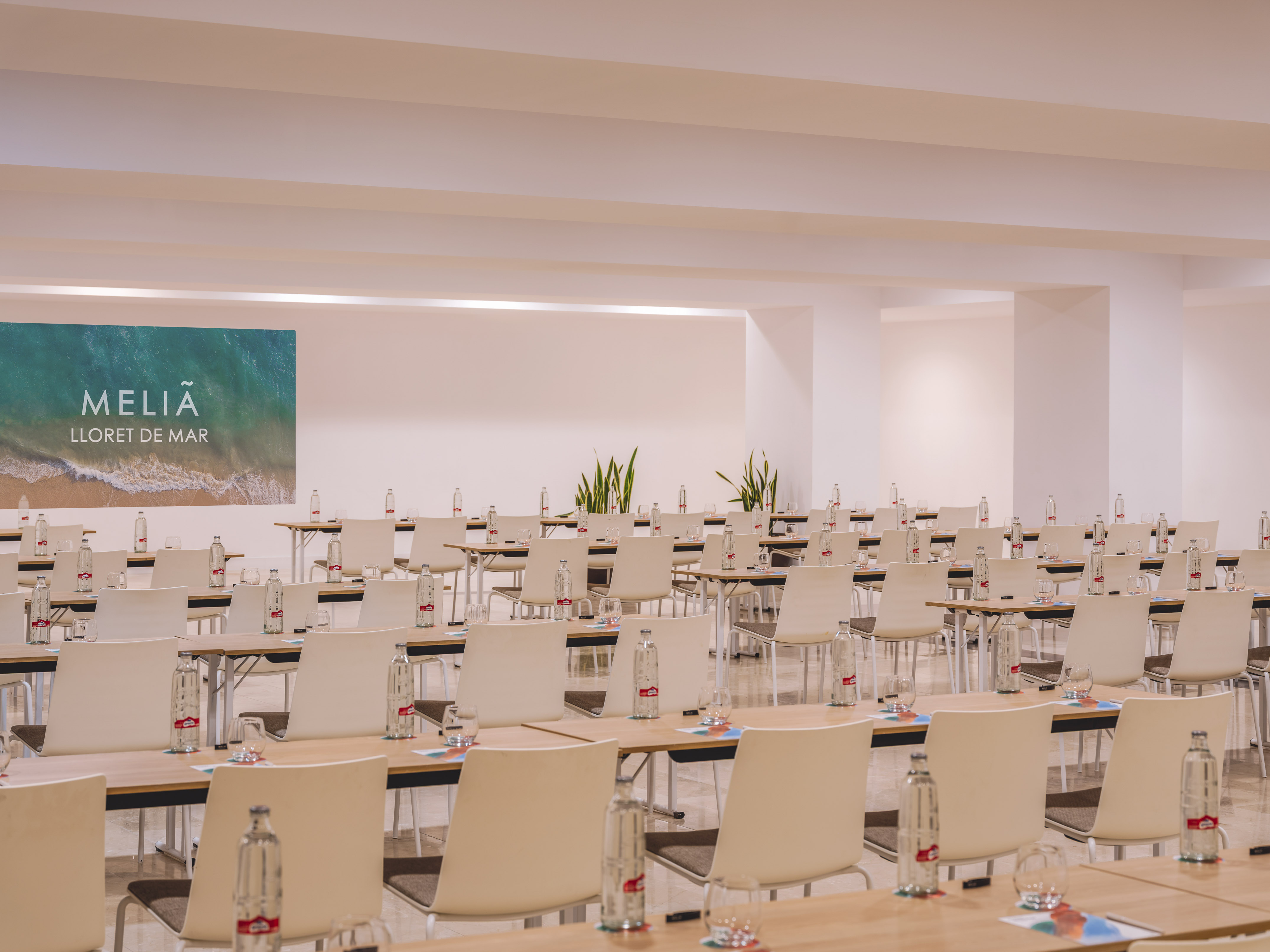 Meliá Lloret de Mar event room setup with tables, chairs, and bottled water.
