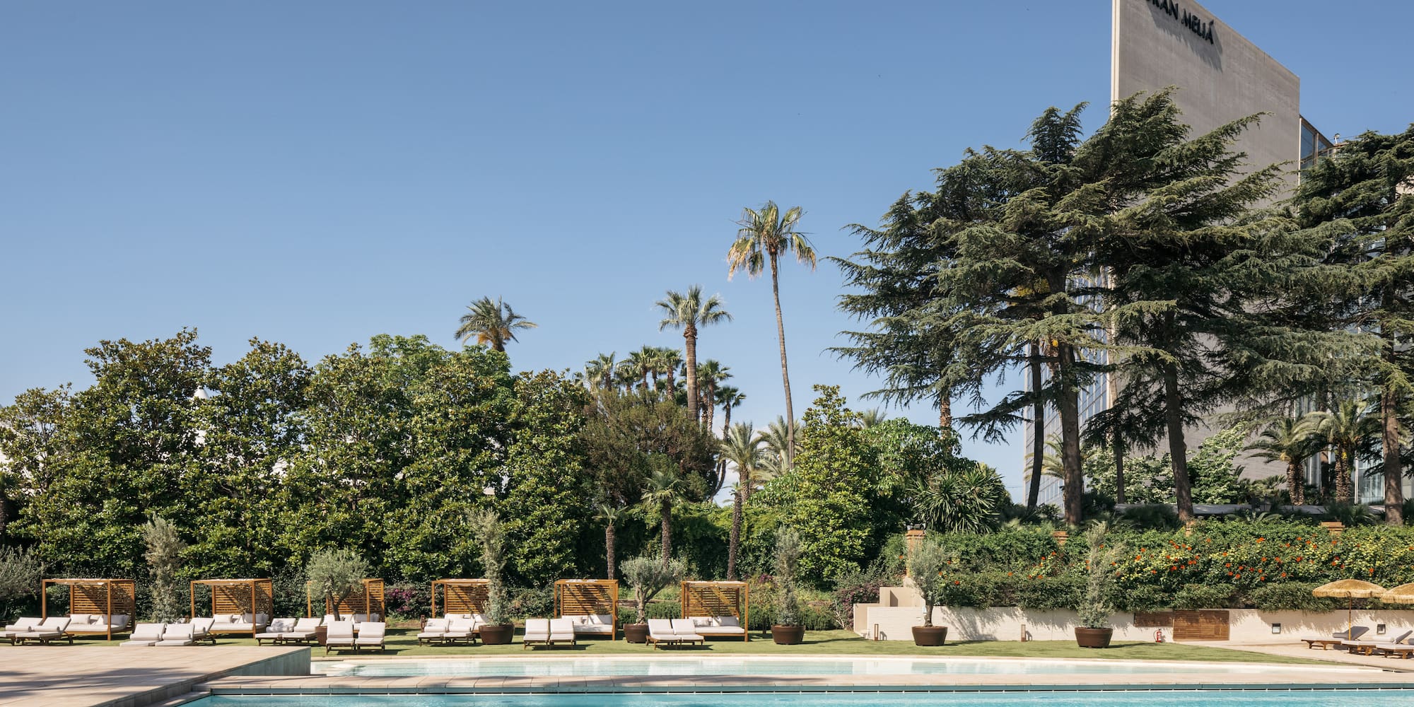 a pool with lounge chairs and trees in the background