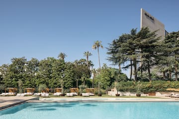 a pool with lounge chairs and trees in the background