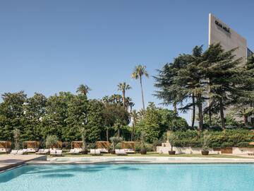a pool with lounge chairs and trees in the background