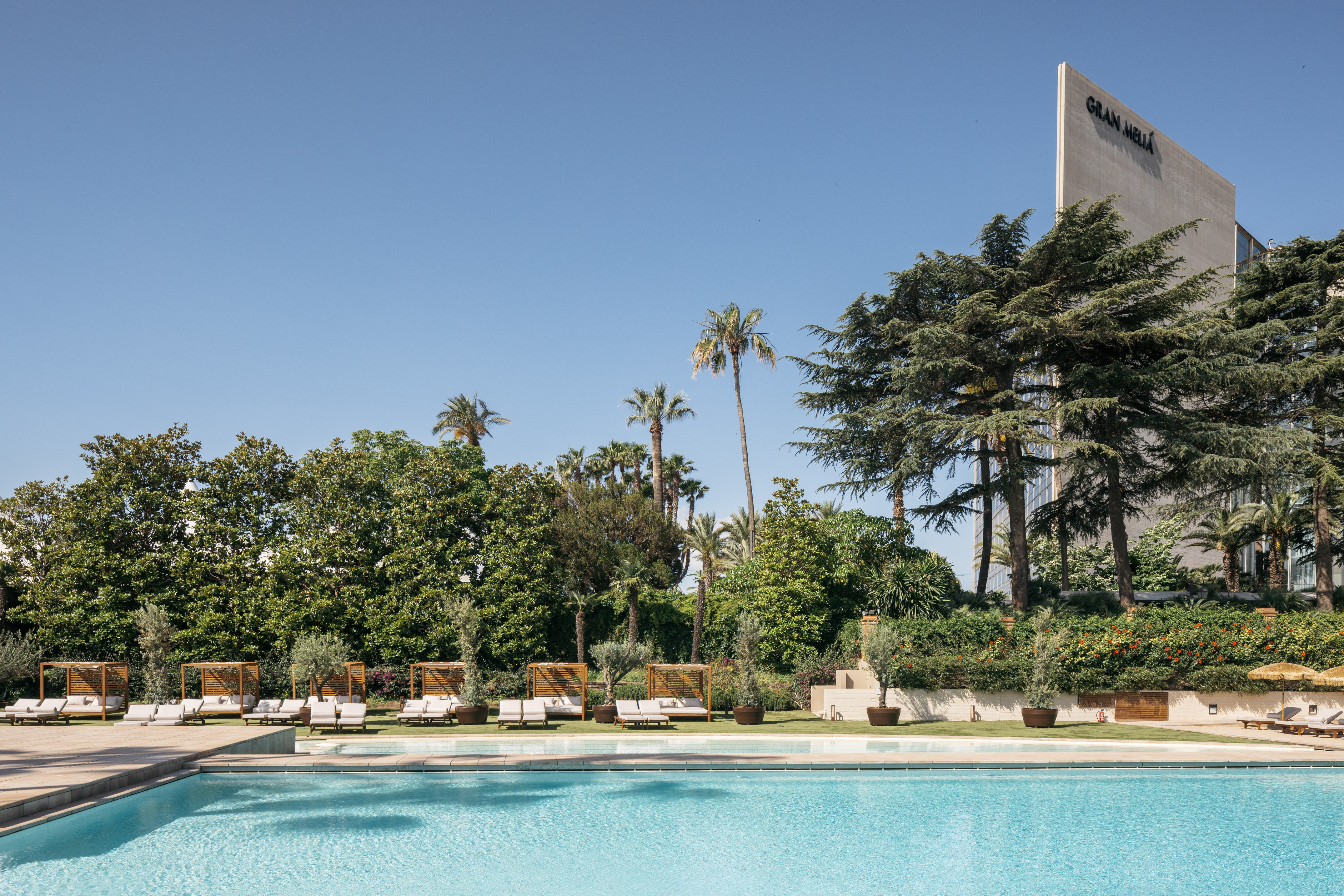 a pool with lounge chairs and trees in the background