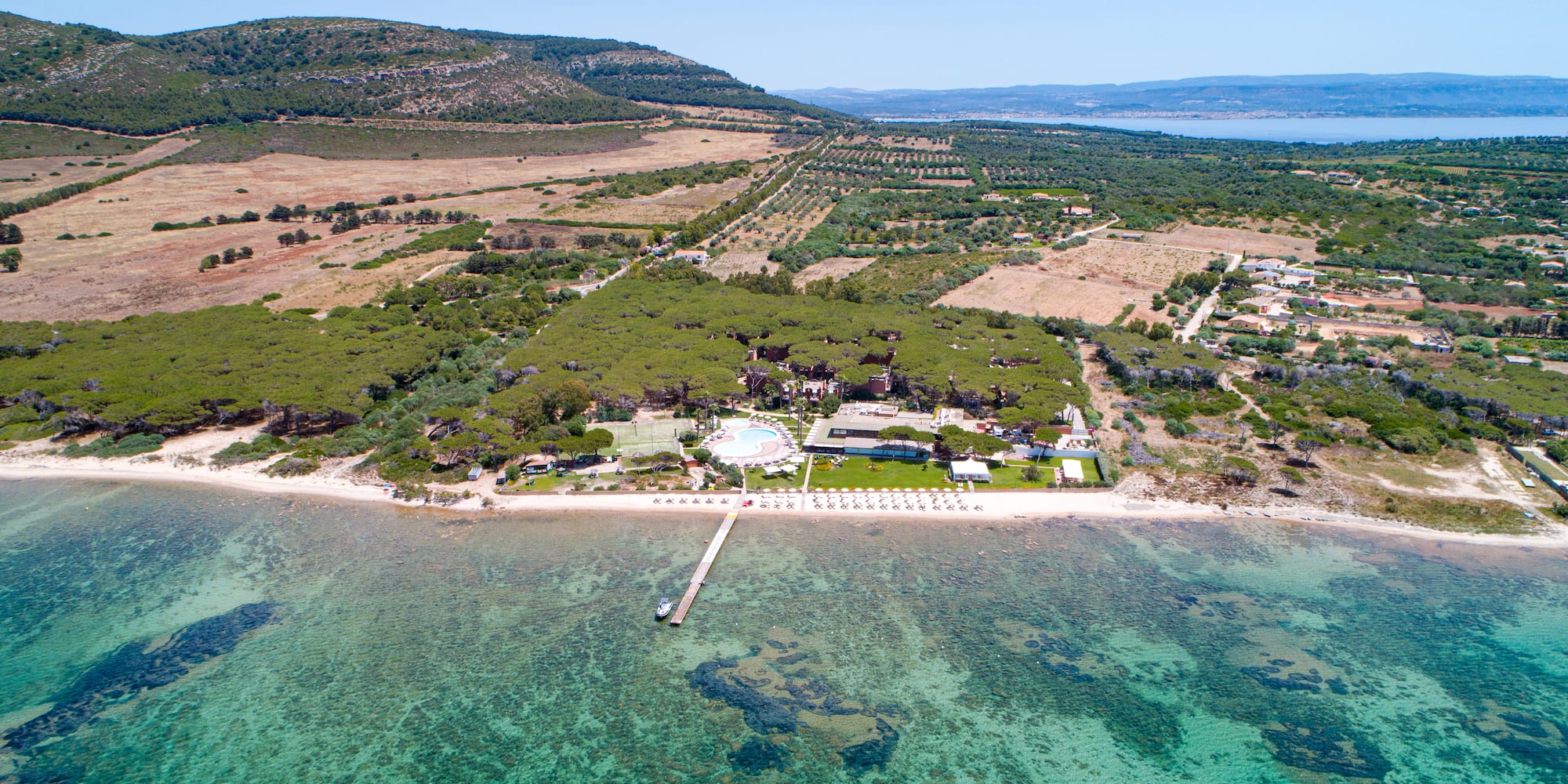 an aerial view of a beach with a pool and trees