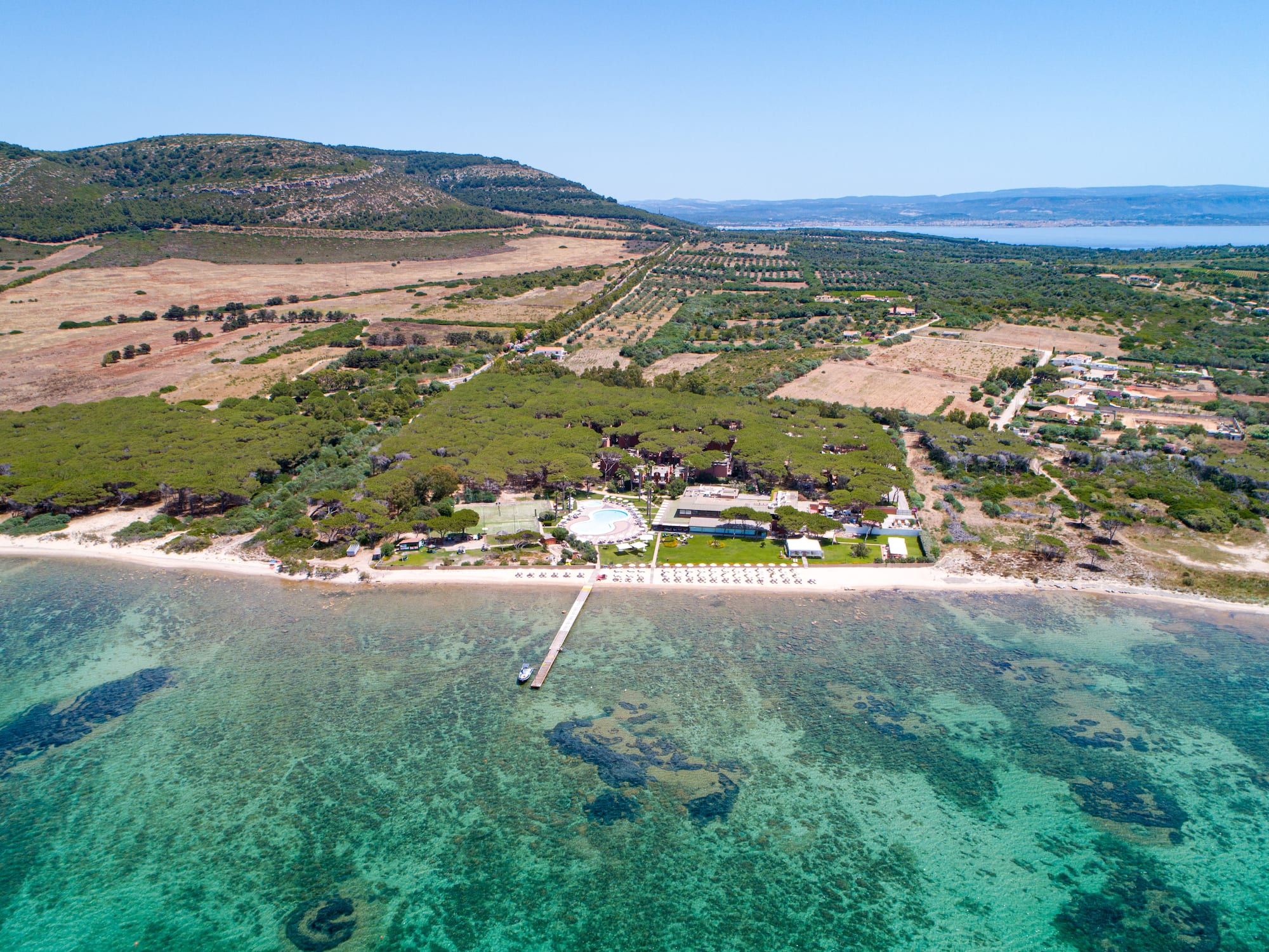 an aerial view of a beach with a pool and trees