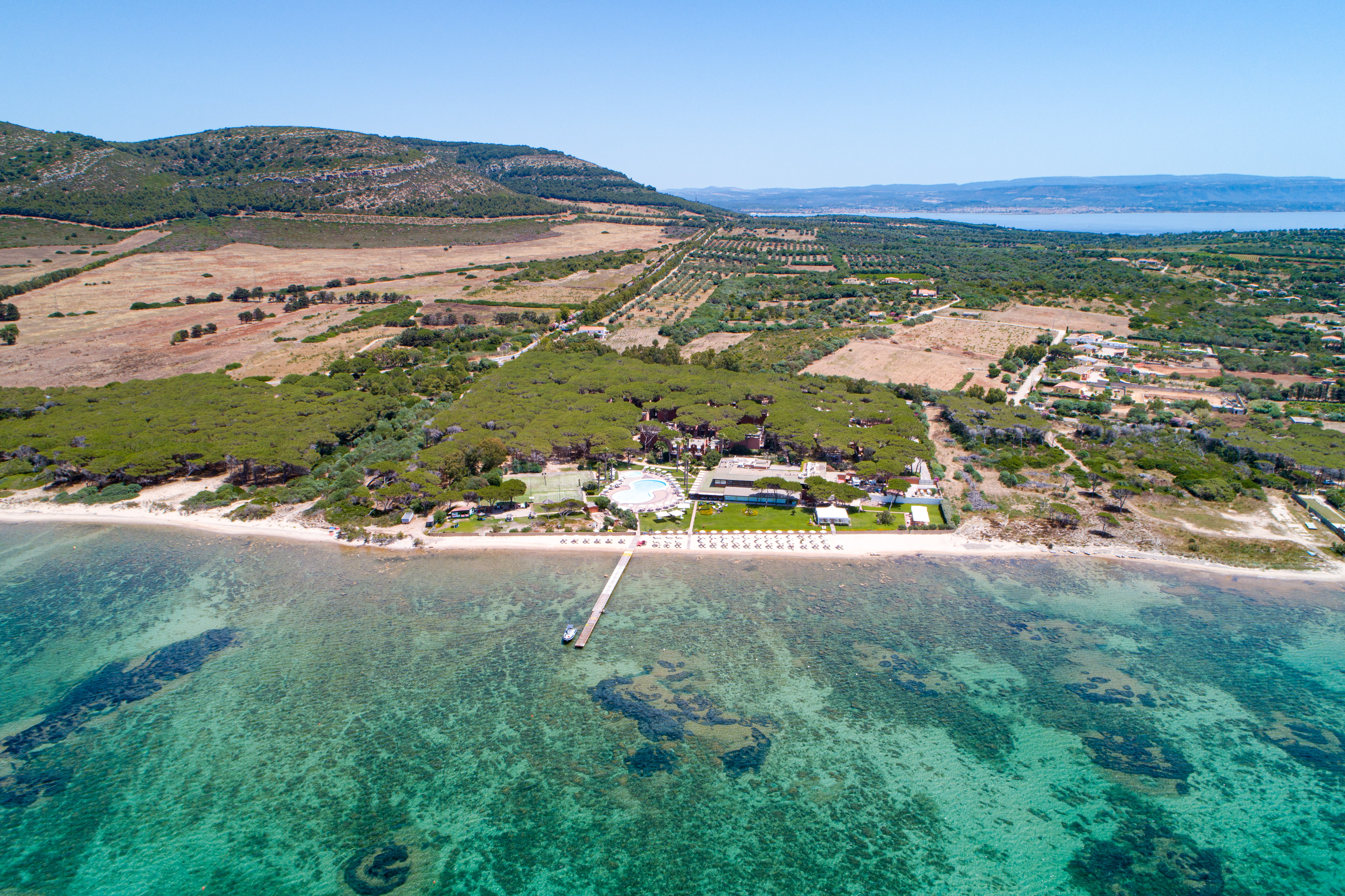 an aerial view of a beach with a pool and trees