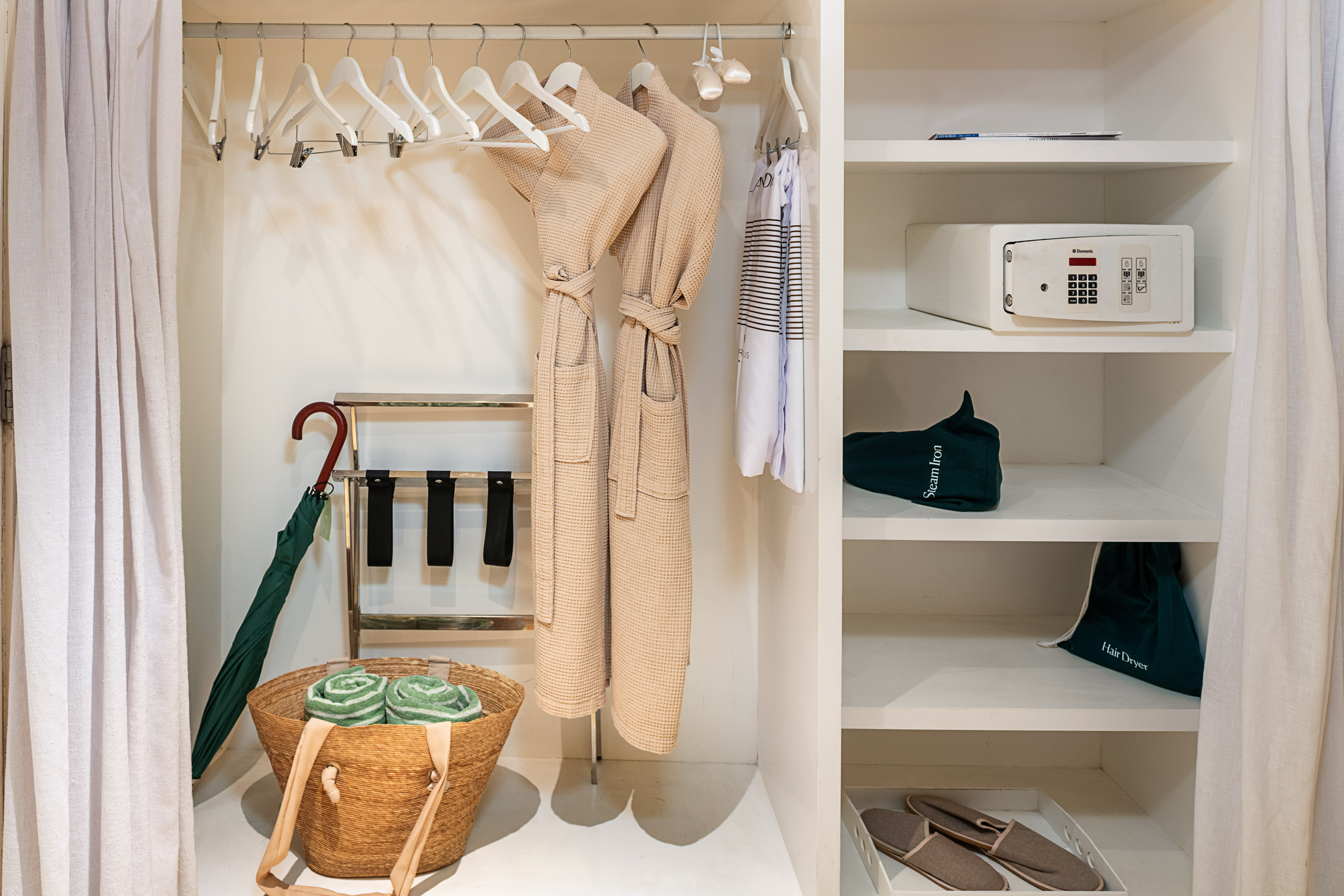 Hotel closet with bathrobes, safe, luggage rack, umbrella, and amenities.