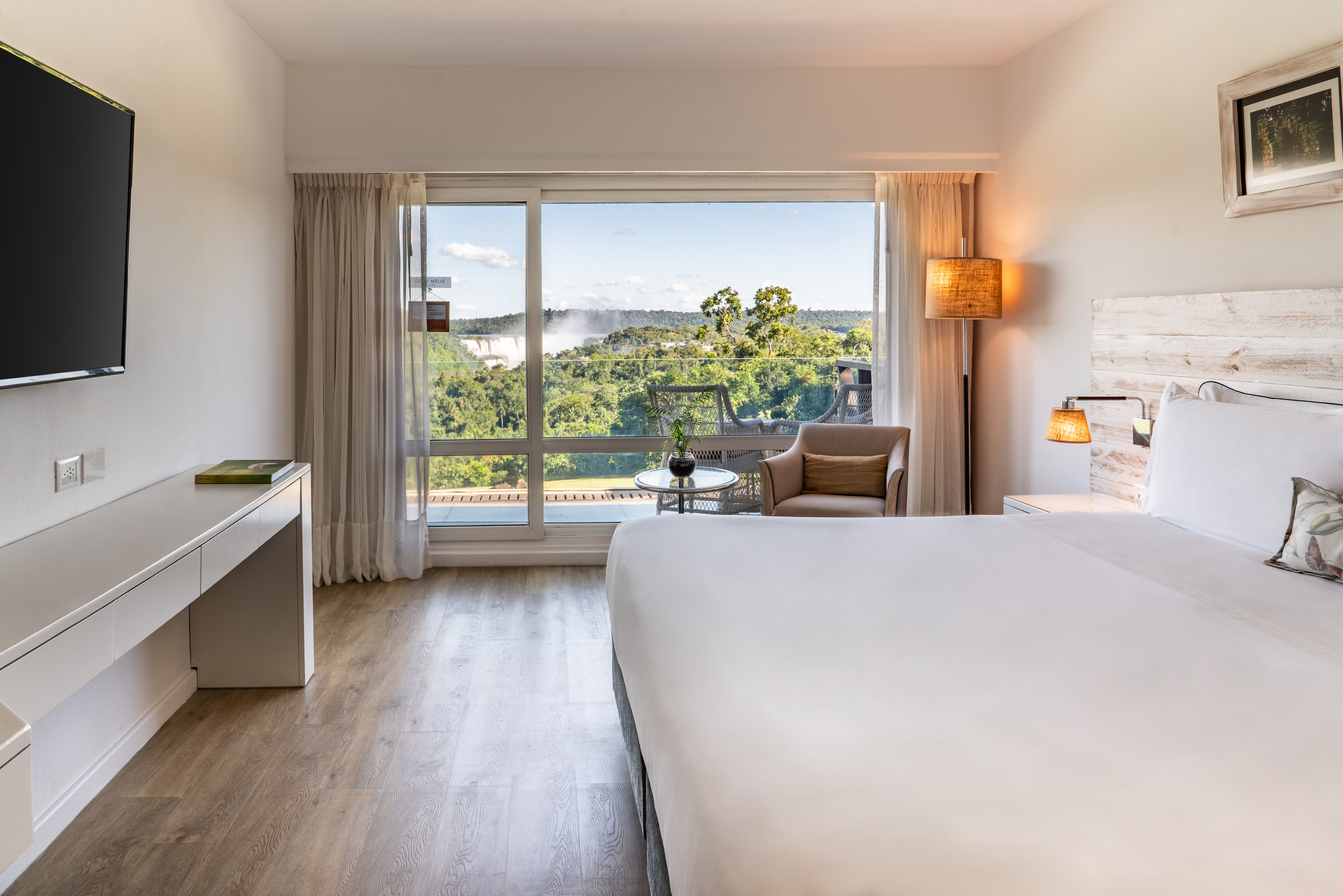 Luxury hotel room with balcony, forest, and Iguazu Falls view.